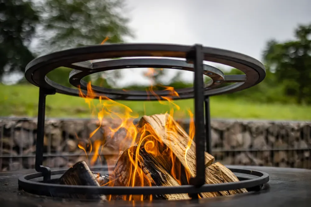 Close-up of burning firewood logs inside a metal backyard fire pit with flames flickering outdoors.