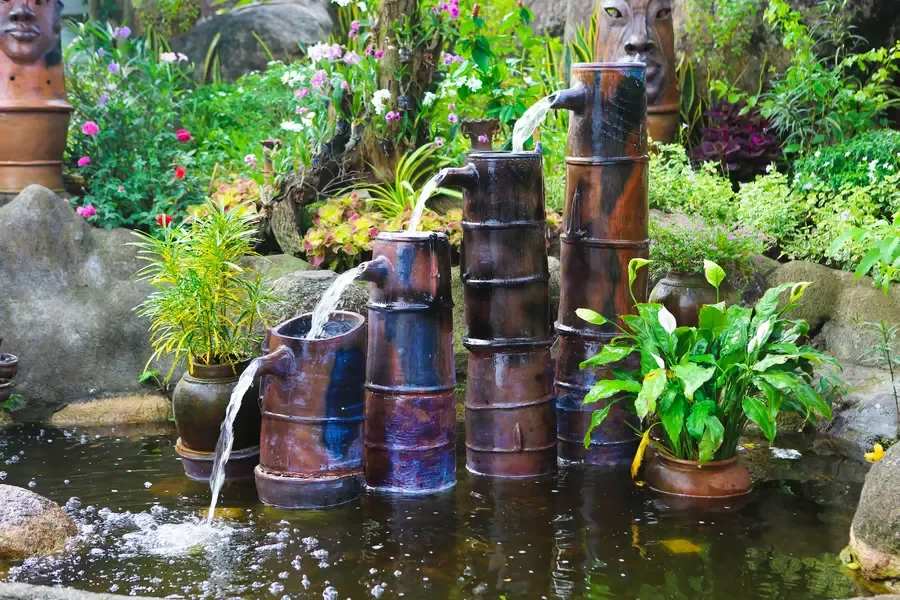Tiered bamboo-style ceramic fountain cascading water down four levels into a garden pond.