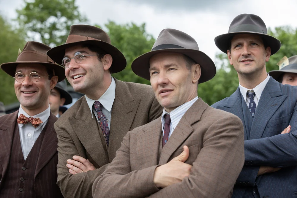 BITB_13244_R(l-r.) Chris Diamantopoulos stars as Royal Brougham, James Wolk as Coach Bolles,and Joel Edgerton as Al Ulbrickson in director George Clooney’sTHE BOYS IN THE BOATAn Amazon MGM Studios filmPhoto credit: Laurie Sparham© 2023 Metro-Goldwyn-Mayer Pictures Inc. All Rights Reserved.