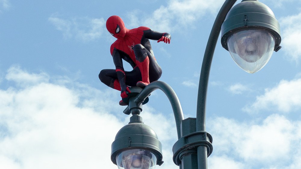 Spider-Man perches on a street light.