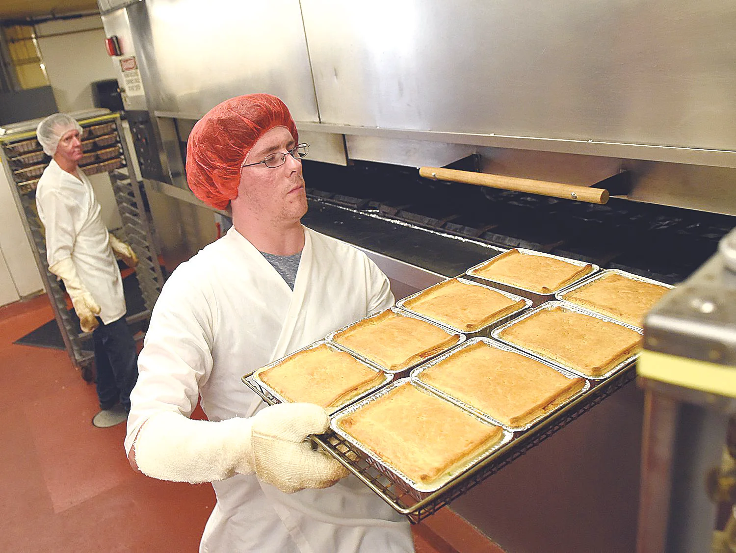 9/8/15--Adam Miller of Manchester removes a tray of chicken pies from the oven at Mrs. Budd's in on Tuesday. DAVID LANE/UNION LEADER