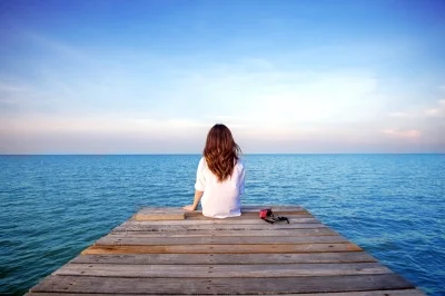 Girl_sitting_alone_on_a Wooden_bridge_on_the_sea_by_tawatchai.jpg