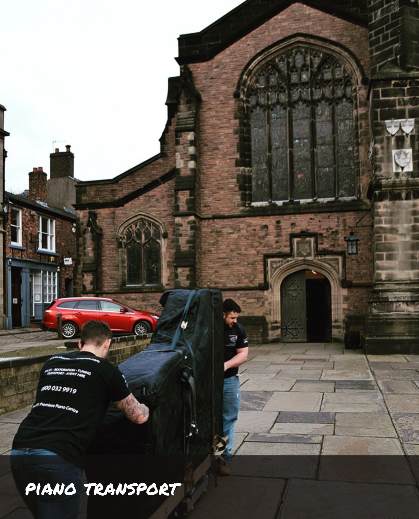 Two people pushing a grand piano into a church