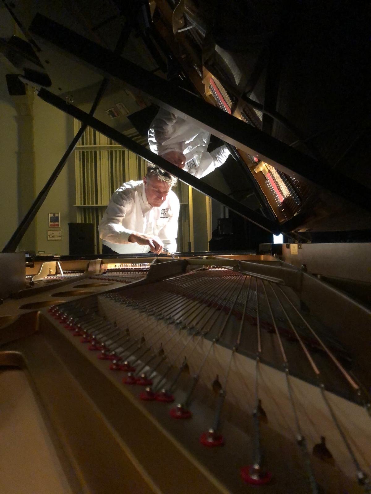 Someone tuning a grand piano