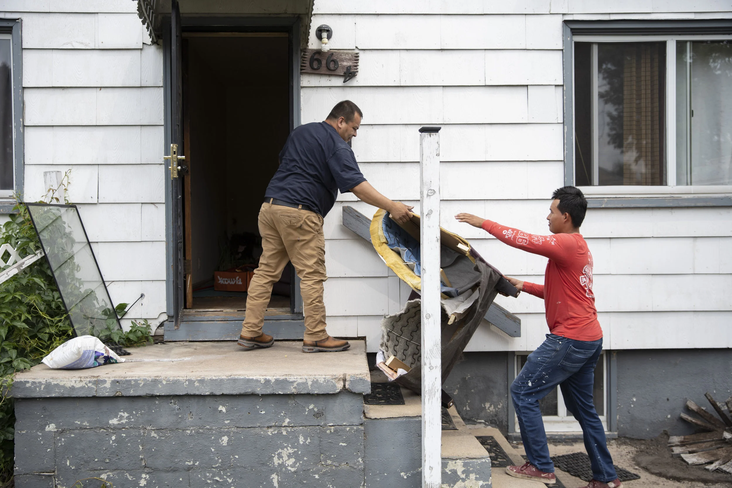 Working on a complete interior remodel, Edgardo hands a piece of a broken down couch to one of his employees, Jayro Rodriguez. Jayro is also from El Salvador, but since his wife is Mexican and is a citizen of the United States, he is also a citizen.