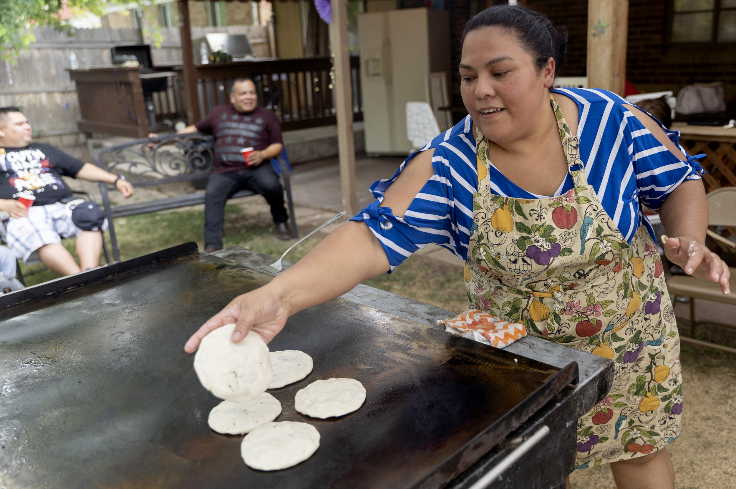 Edgardo’s friend Janet throws some pupusas on the flattop in Edgardo's backyard during Edgardo's birthday party. Of the 20 or so friends in attendance, more than half are in the United States through TPS. Edgardo worked two long days in a row so he could take his birthday off for this party.
