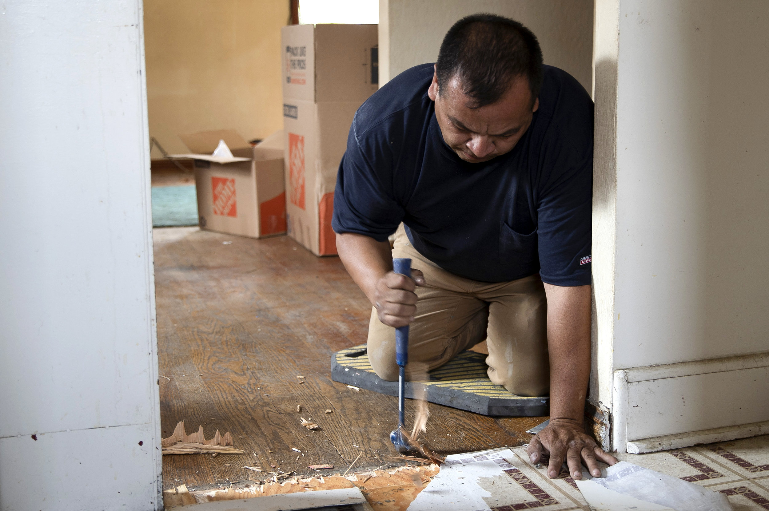 Edgardo works on removing the linoleum floor from a kitchen in a home that he is renovating. Edgardo never uses gloves when he works. He said his father nor his grandfather never used gloves, so he never does either.