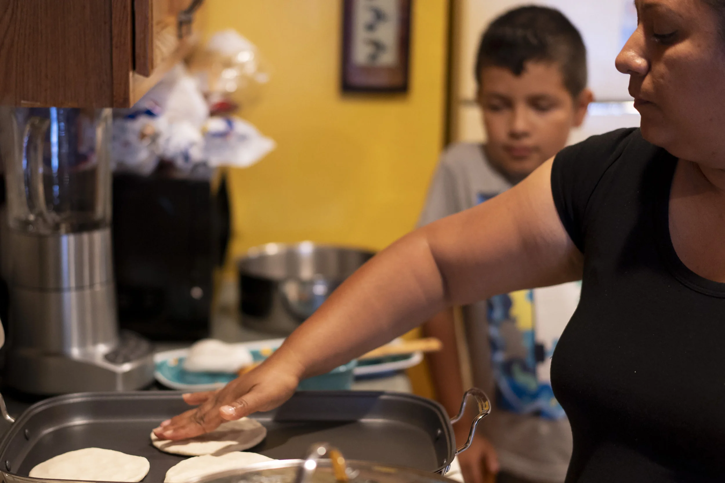 Marlon, watches his mother makes traditional tortillas from maseca, for a dinner party they are hosting for some friends.