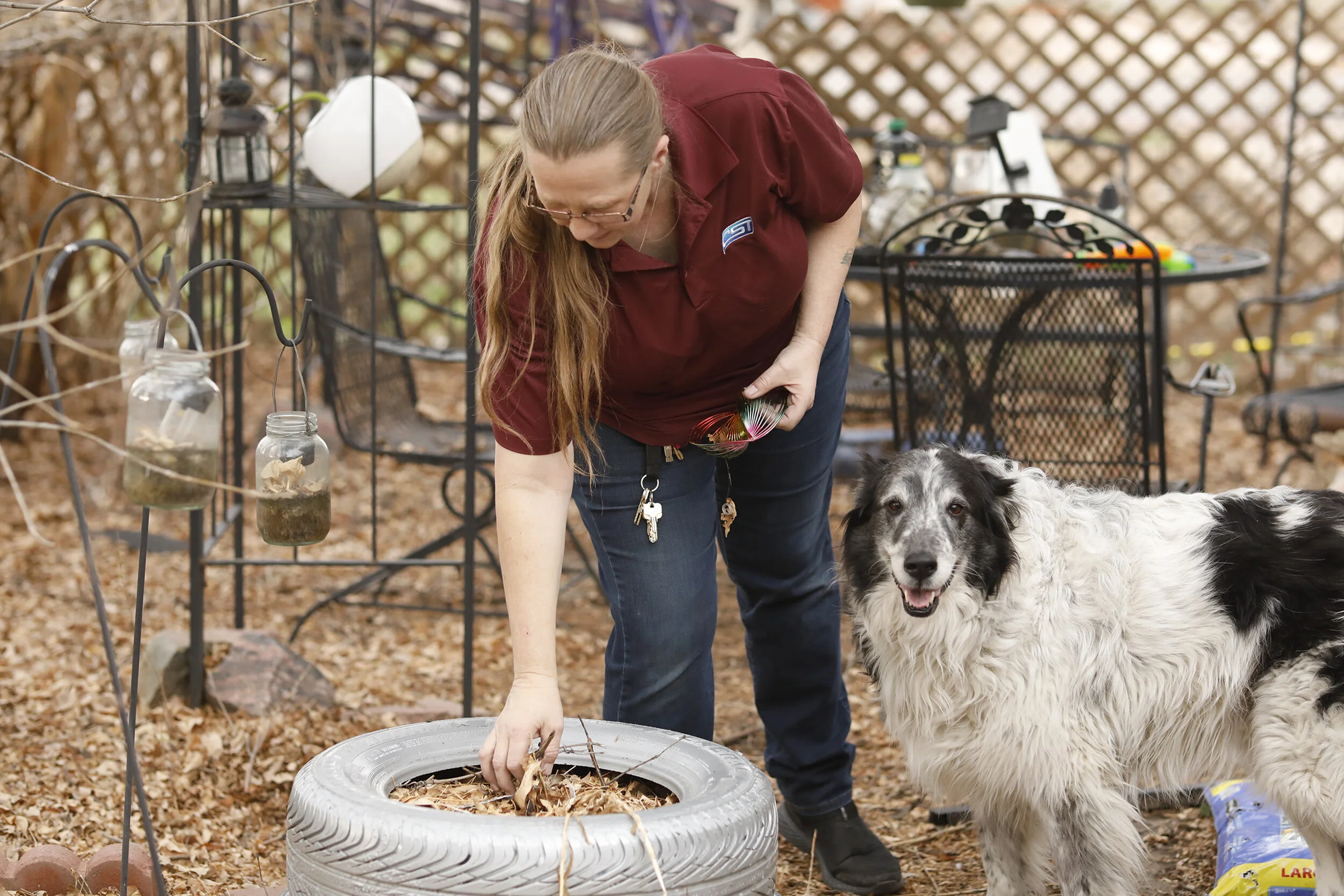 Petra Bennett, who loves her back yard, and spends most of her time there, when at home, cleans out a planter, which is made of tires stacked on top of one another, March 30, 2018.