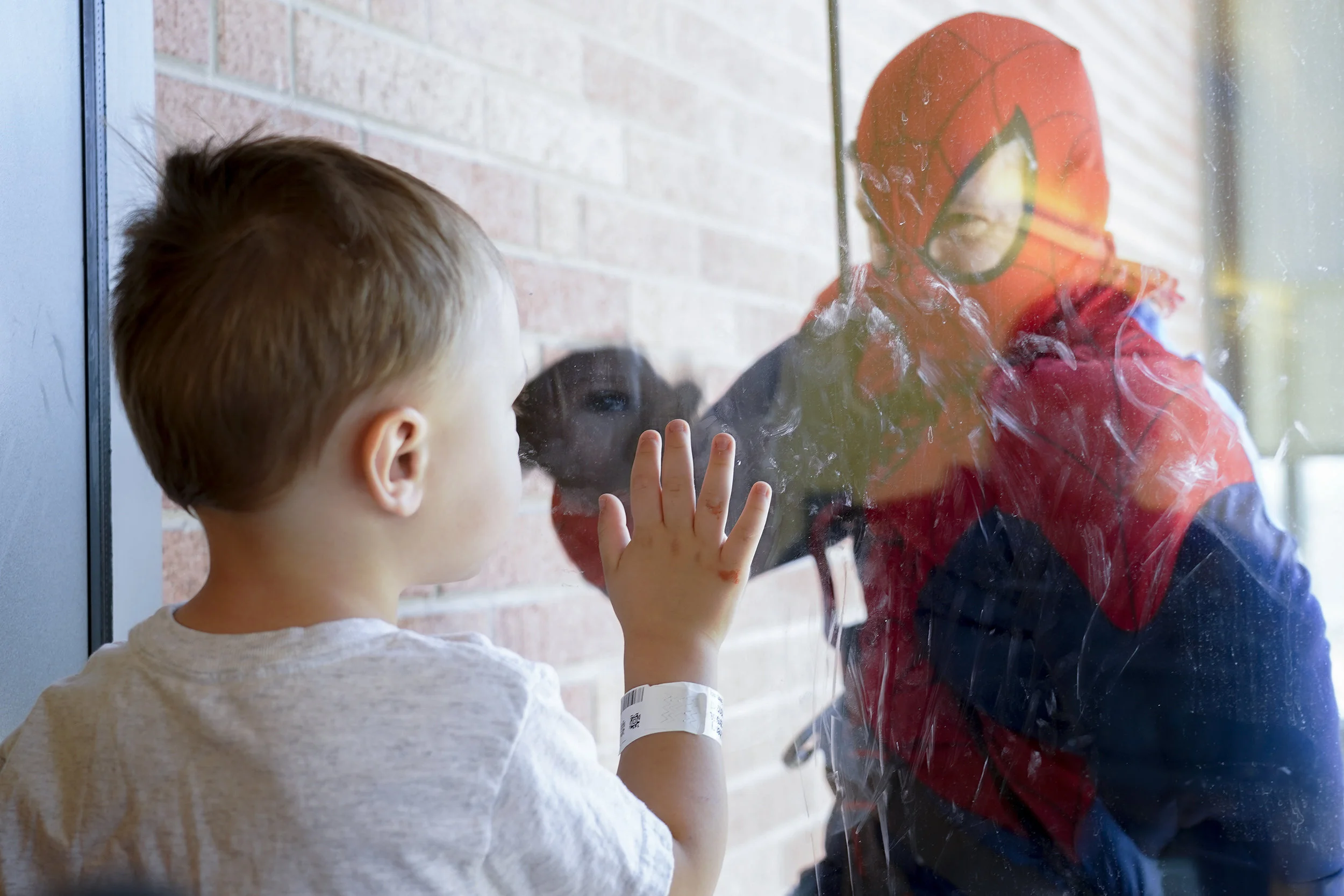 Henry Diamond, 2, waves to Officer Brady, dressed as Spiderman, Aug. 22, at Children's Hospital Colorado. Aurora Police Officers spent their morning rappelling down the side of the hospital passing windows for children to see.