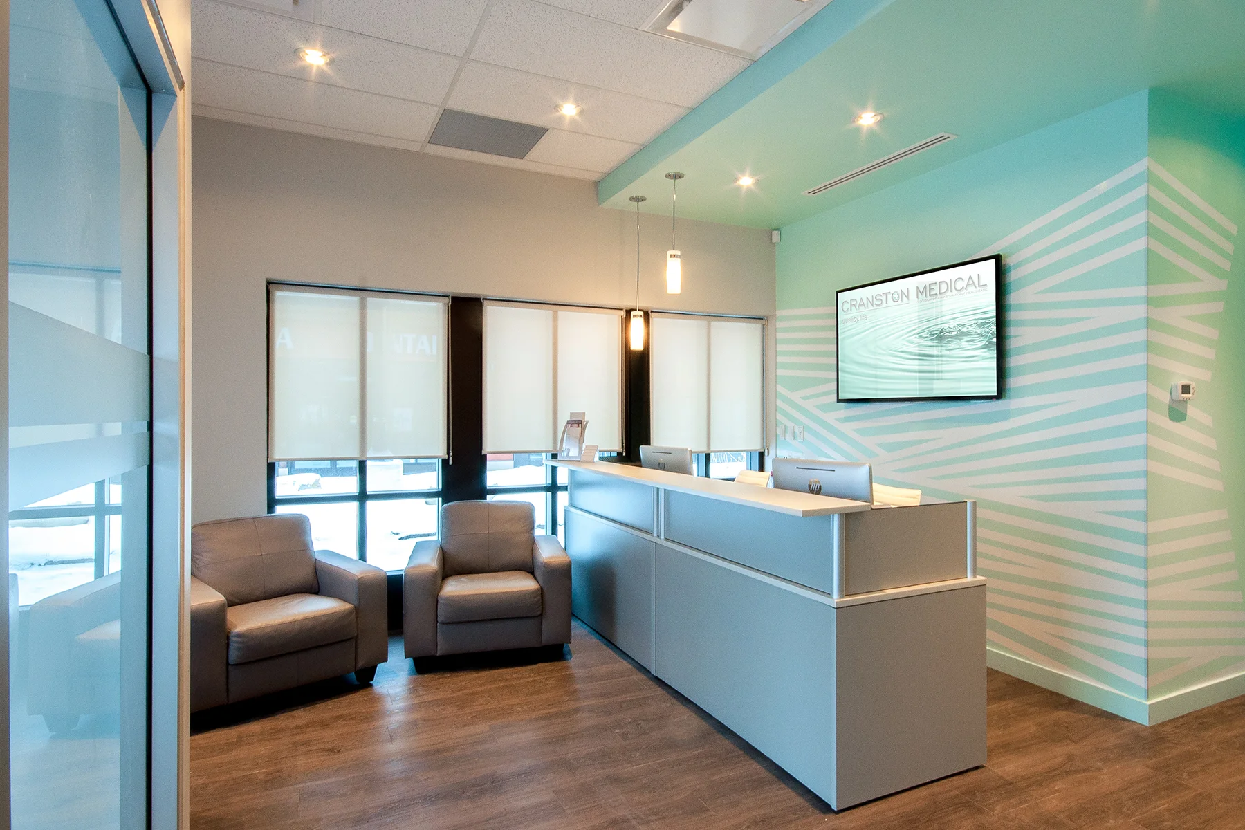 Cranston Medical Clinic Cranston, Calgary 2014 A project completed under the constraints of a limited budget and limited construction schedule. Strips of white vinyl applied in a unique pattern create a low-cost custom look behind the desk.