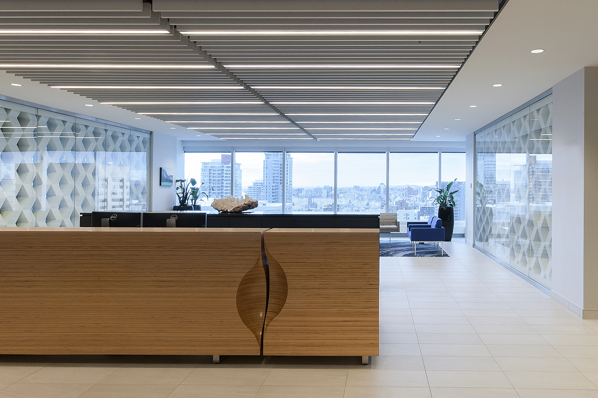 Clean lines and crisp finishes define the final design for this corporate office renovation project. An exposed-edge plywood reception desk anchors the space with custom rugs, Herman Miller furniture, and Modularts dividers complimenting it.