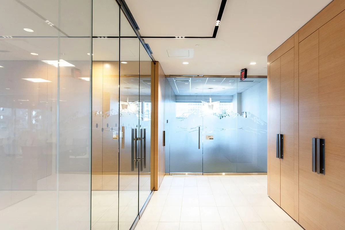 Clean lines and crisp finishes define the final design for this corporate office renovation project. An exposed-edge plywood reception desk anchors the space with custom rugs, Herman Miller furniture, and Modularts dividers complimenting it.