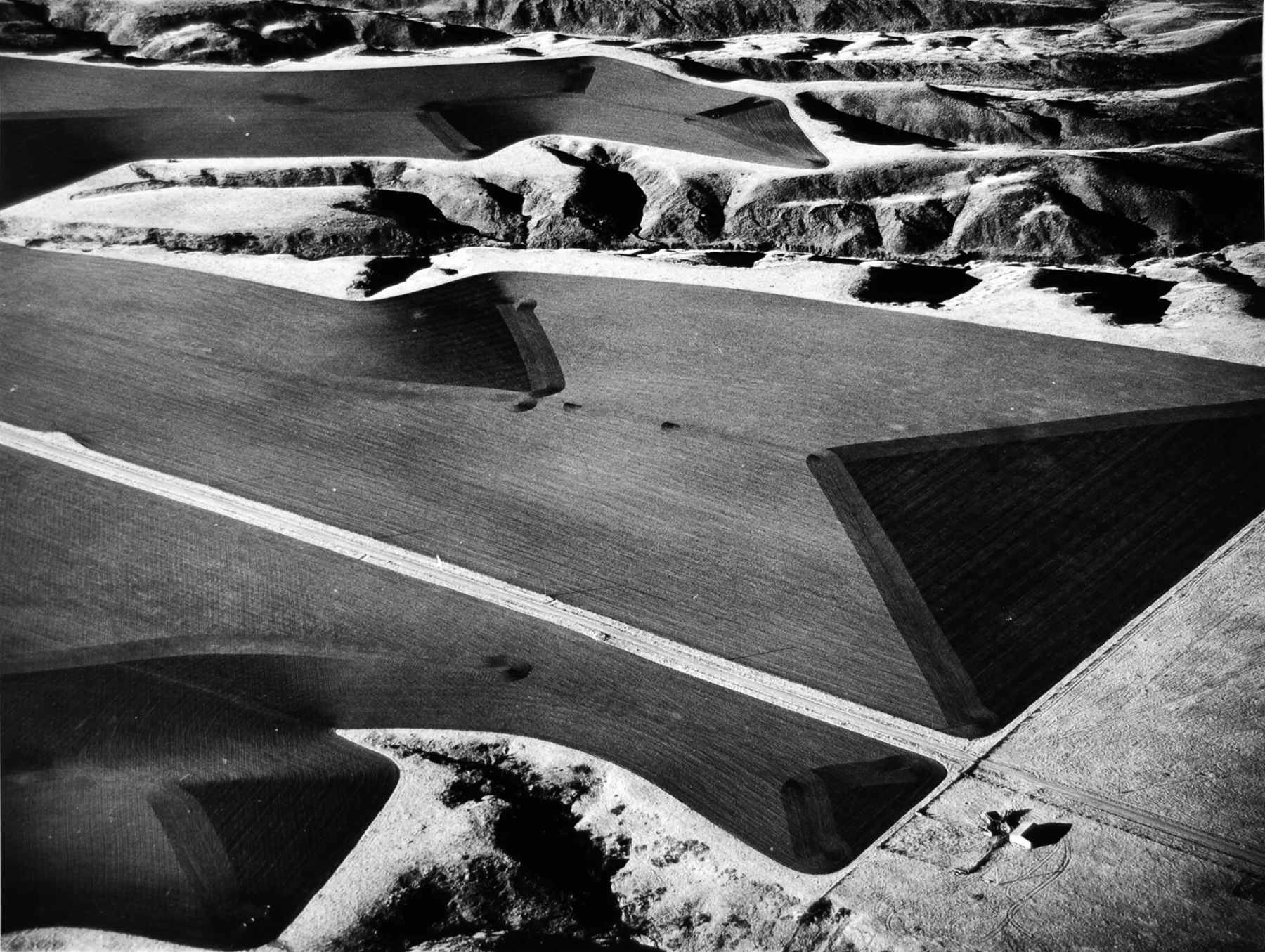 Marilyn Bridges (American, b. 1948), Farmer's Edge, South Dakota, 1984; 2011:314 In 1976, upon seeing the Nazca Indian "runway" lines in Peru, Marilyn Bridges decided to become a pilot. Bridges is credentialed to fly single- and multi-engine land and sea aircraft, and she even owns her own Cessna, but she does not pilot when she photographs. Waiting for just the right light, she directs the pilot where to fly and when to tilt in angles ranging from low oblique to vertical to get the right picture. The process is technically demanding both in terms of flying--the plane must slow down to just a notch above stalling even at a shutter speed of 1/1000th of a second--and in terms of photographing. Unable to slow the plane any more than she does, Bridges extends the speed of her Tri-X film by pushing it (a development technique). So that her landscapes resonate as land and not as abstractions, she shoots from an altitude no greater than 1000 feet above the earth, and she prefers to get as close as 200 feet. She usually shoots with a 6×7 Pentax medium-format camera, sometimes a Leica 35mm, and always from an open window.