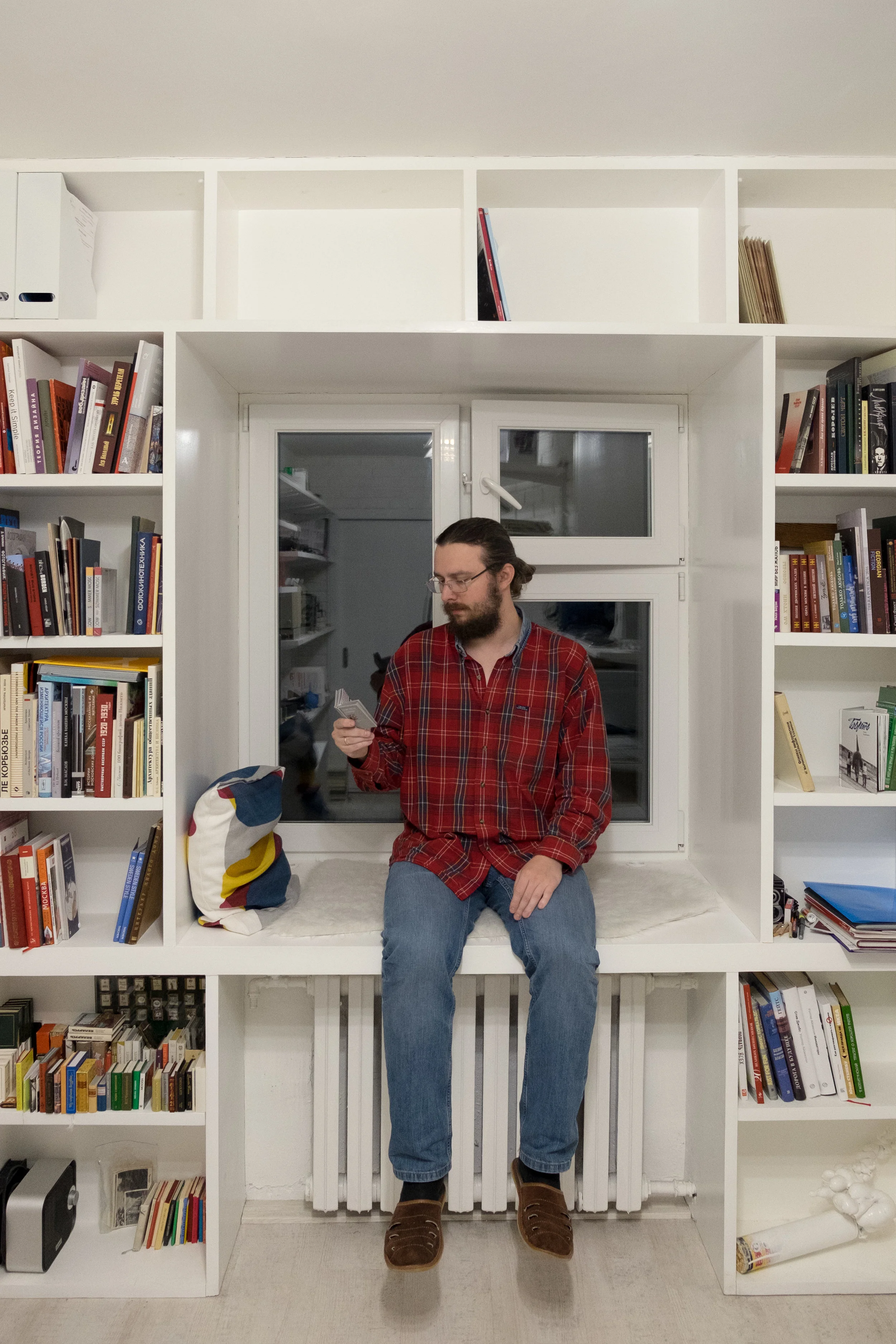 Photographer Mikhail Emelchenkov in his home office viewing a miniature photobook