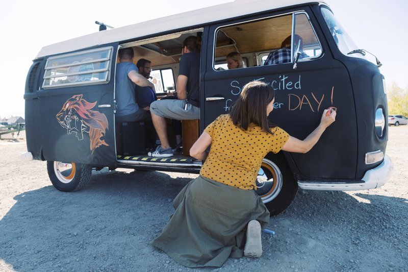 Stacey Squire writes a positive message on one of the doors of the Chalkbus on Saturday, Oct. 26, 2019, in American Fork, Utah. (Michael Schnell/The Daily Herald via AP)