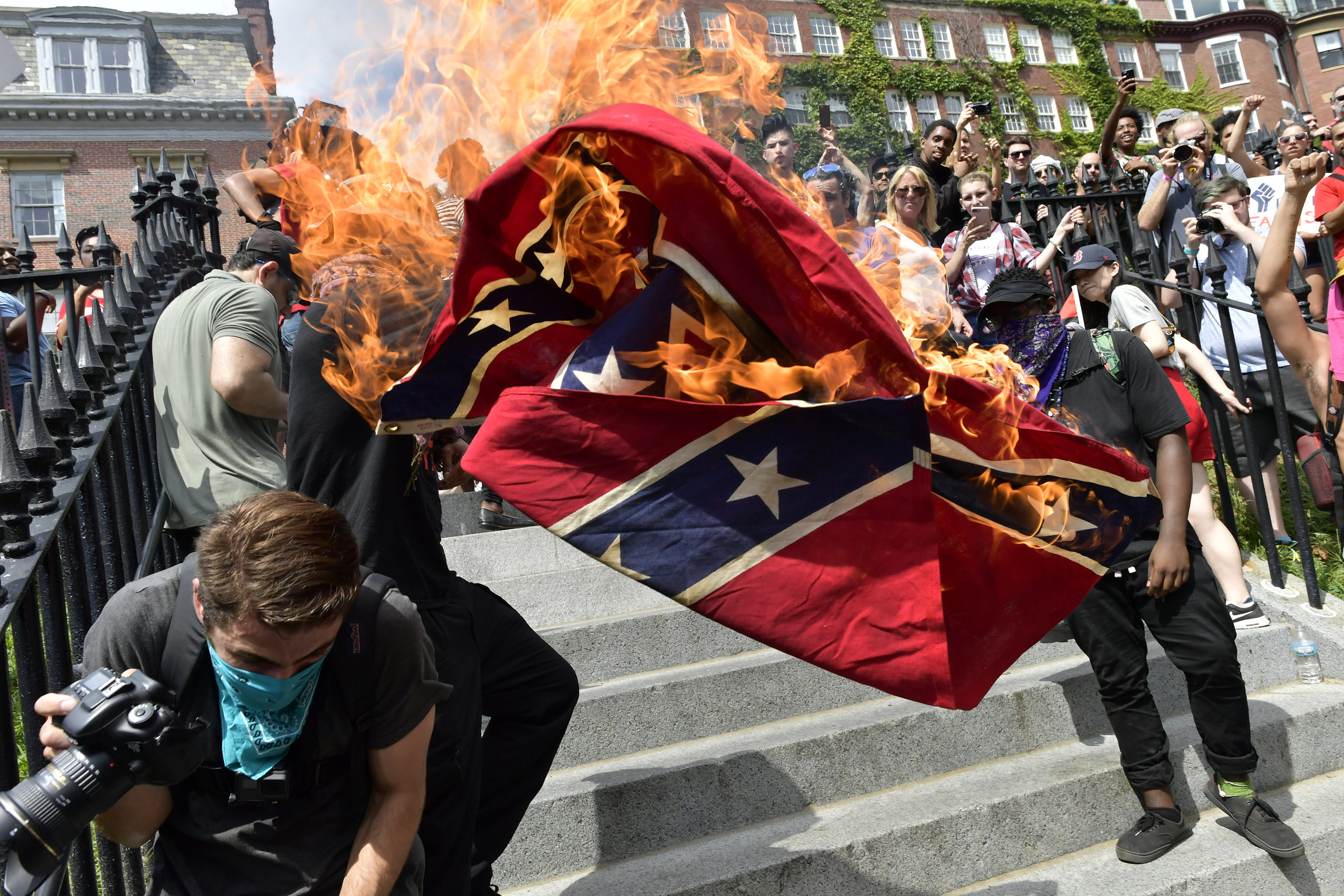  NOTE: THIS IMAGE RECEIVED FIRST PLACE IN THE NPPA AUGUST 2017 MONTHLY CLIP CONTEST FOR THE New England REGION     BOSTON, MA Saturday, August 19, 2017 -- Black Lives Matter protesters burn a Confederate flag as tens of thousands of demonstrators tur