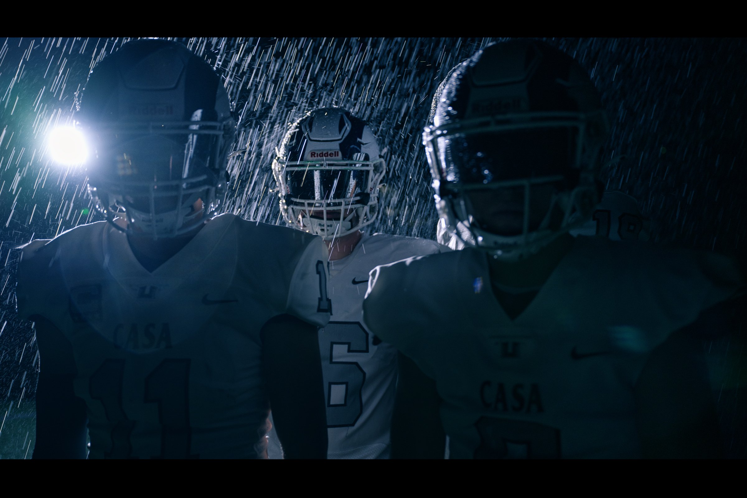 Football players in dramatic low-key lighting with helmet flash, editorial sports photography Sacramento