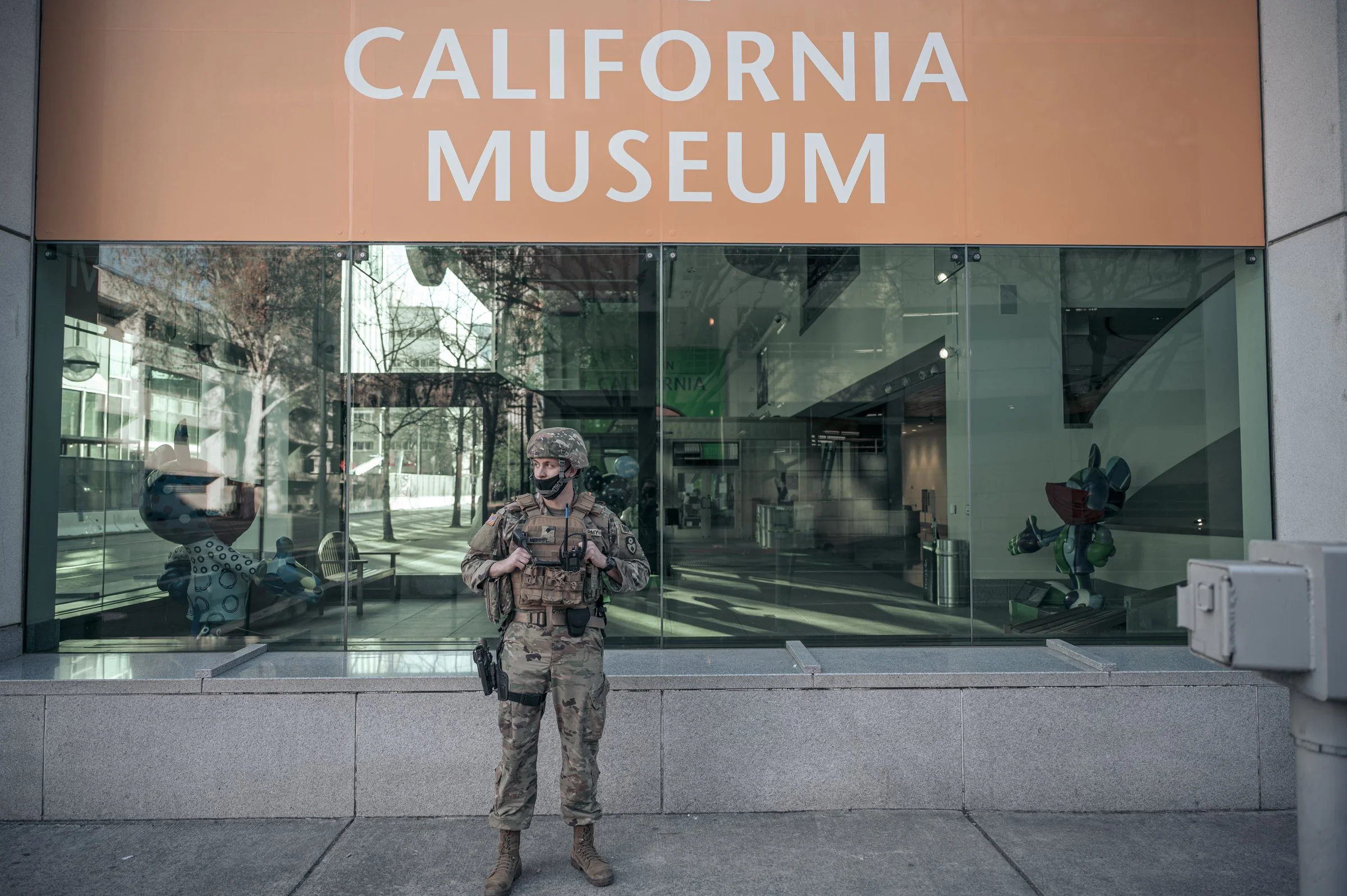 Military soldier in tactical gear outside California Museum entrance, editorial documentary photography Sacramento