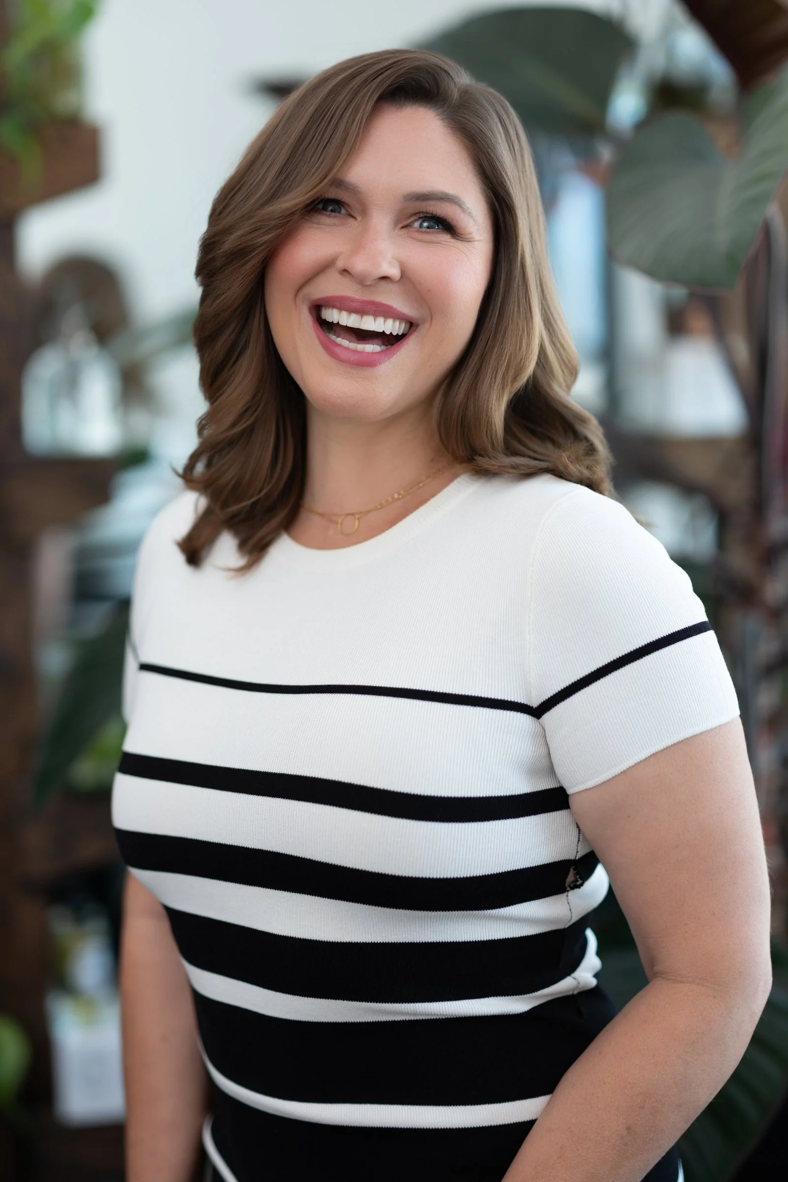 Professional woman in black and white striped top laughing, approachable corporate headshot