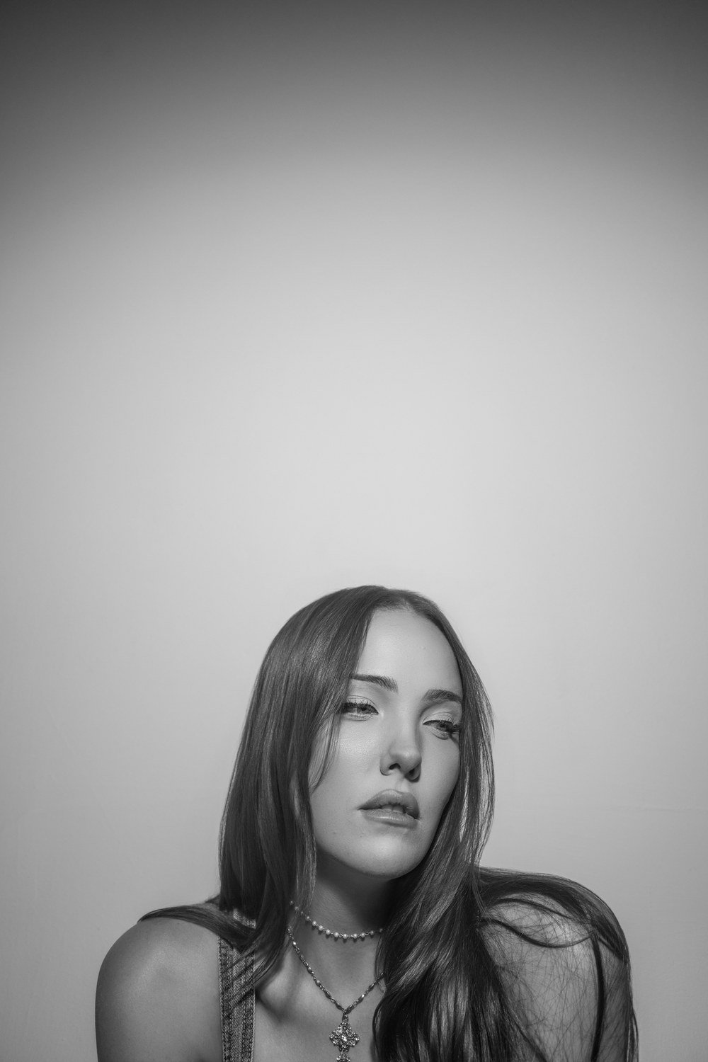 Black-and-white studio portrait of a young woman with long hair against a plain gray backdrop