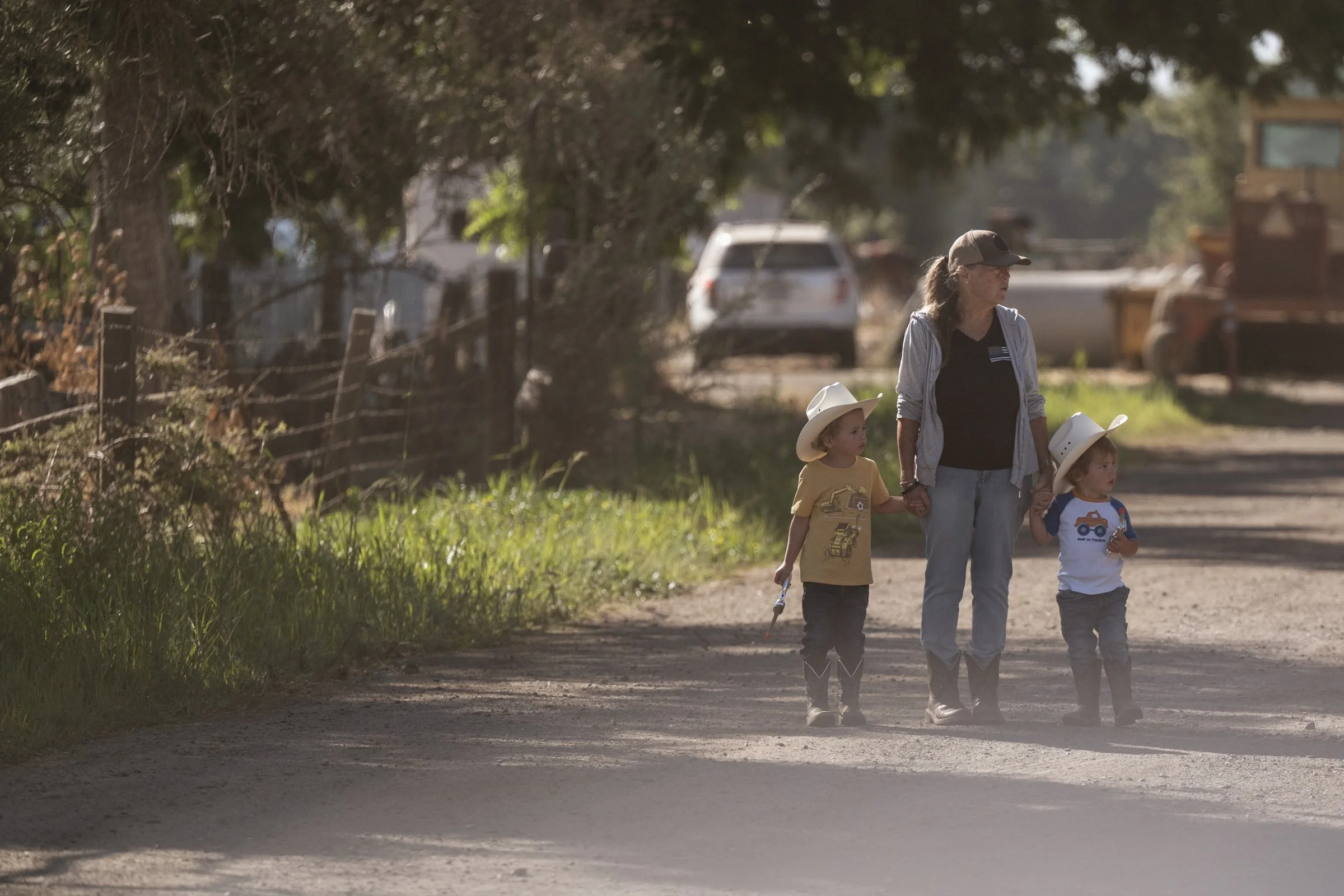 Woman walking two young children in cowboy hats down dirt road at Mahon Ranch Sacramento County California July 2025