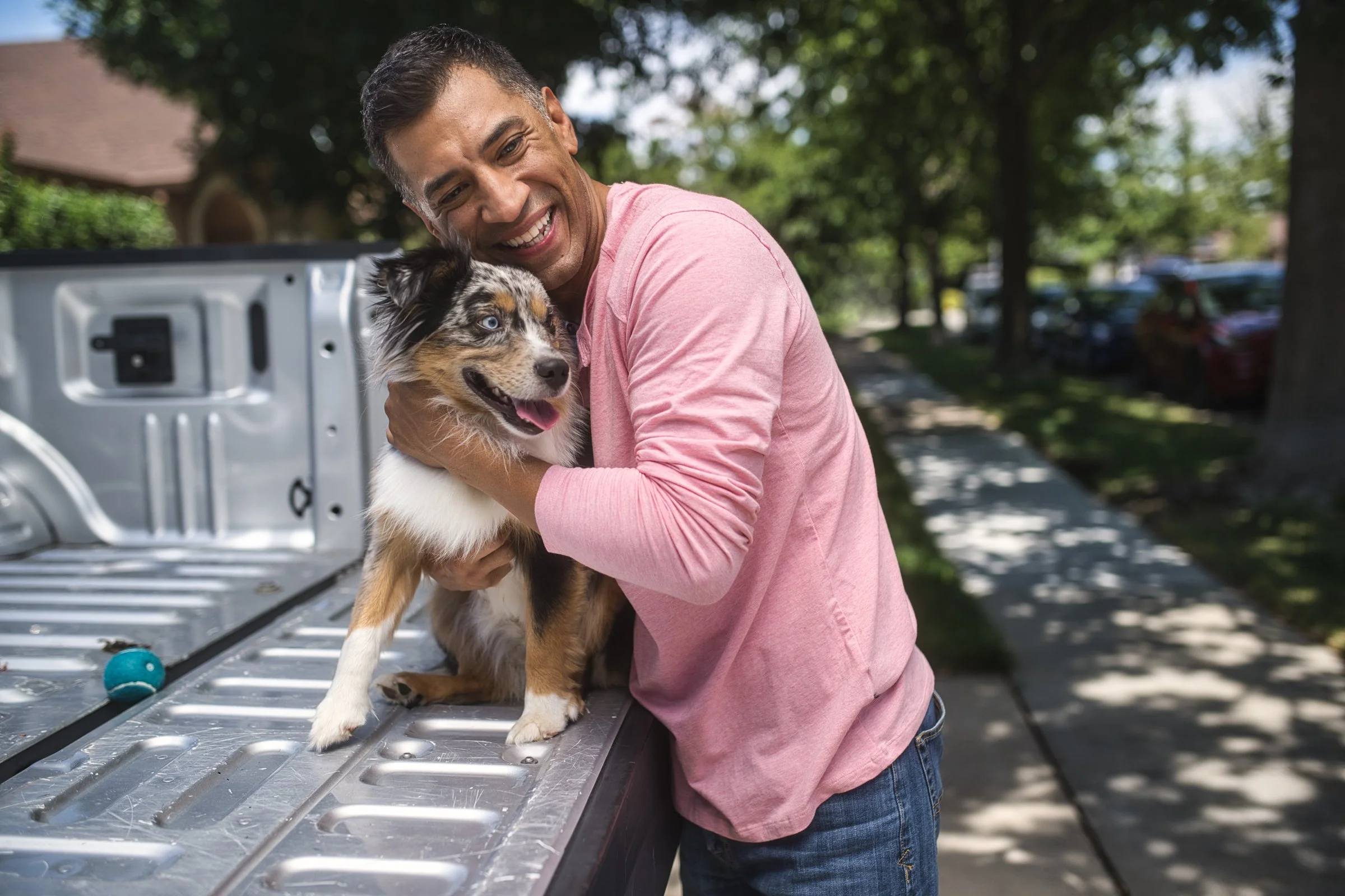 Man holding Australian shepherd dog on truck tailgate, lifestyle brand photography Sacramento