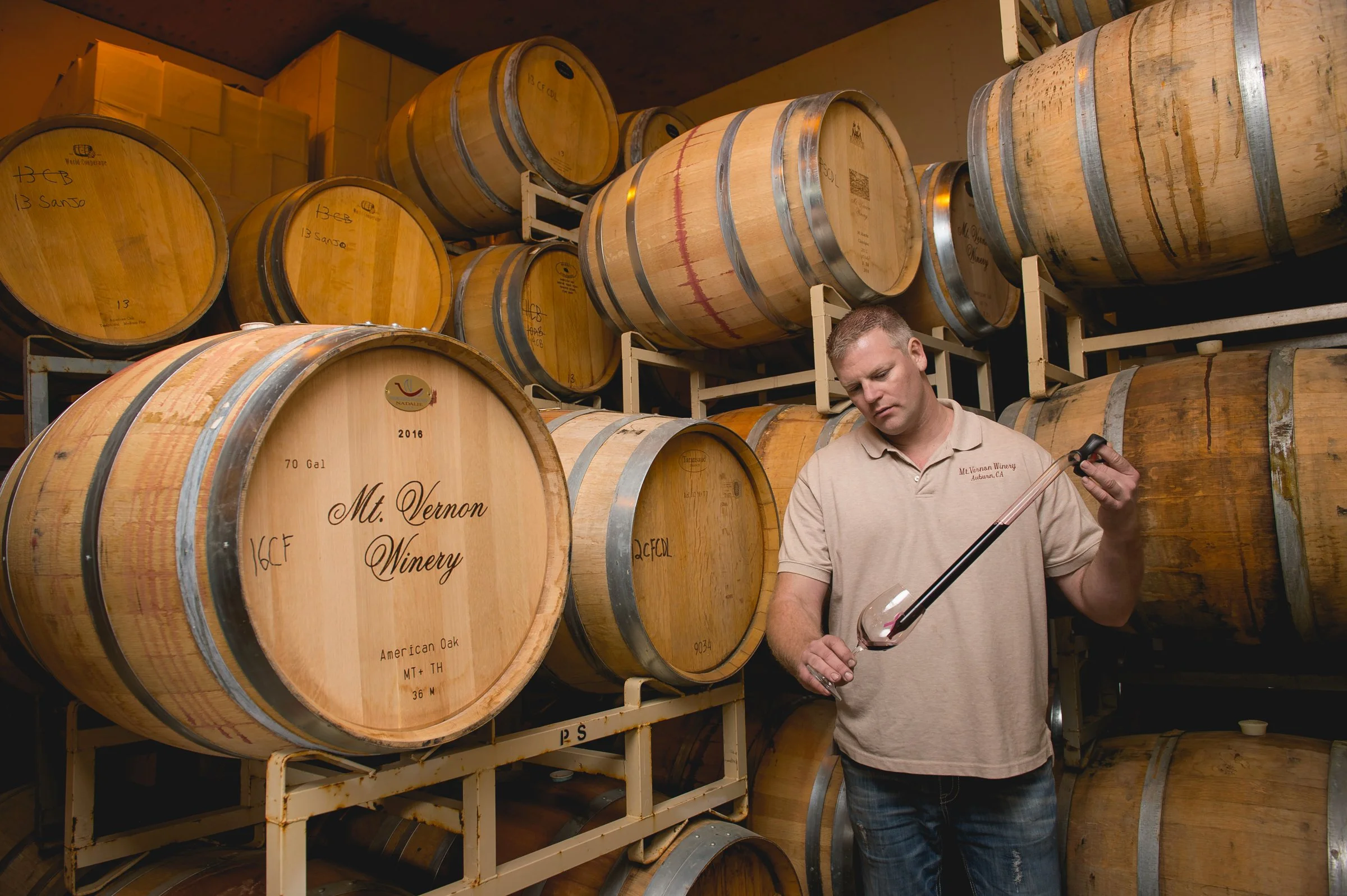 Winemaker beside oak barrels in winery, editorial business portrait Northern California
