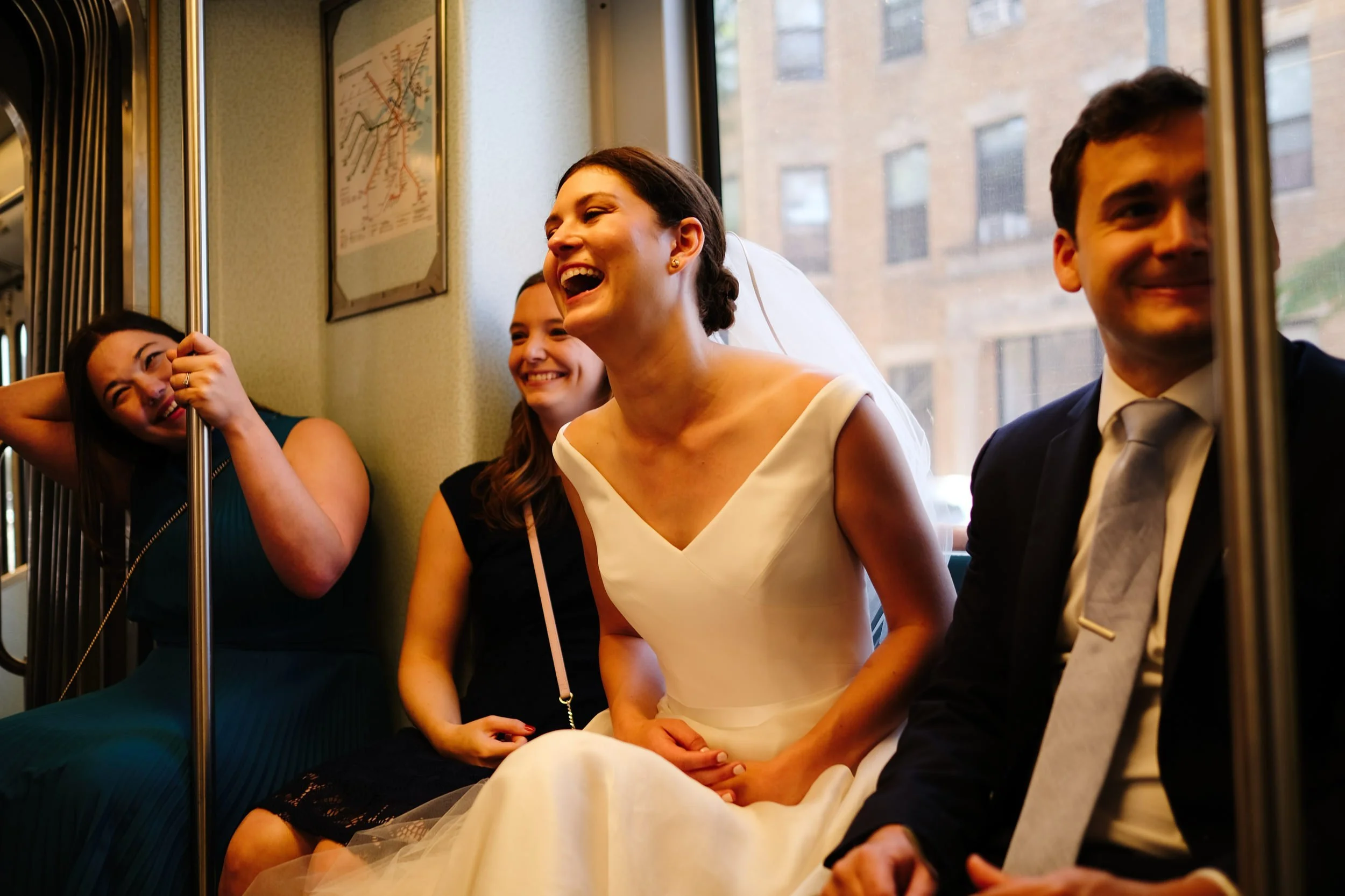 A group of four people, including a woman in a wedding dress, sitting on a bus, laughing and smiling.