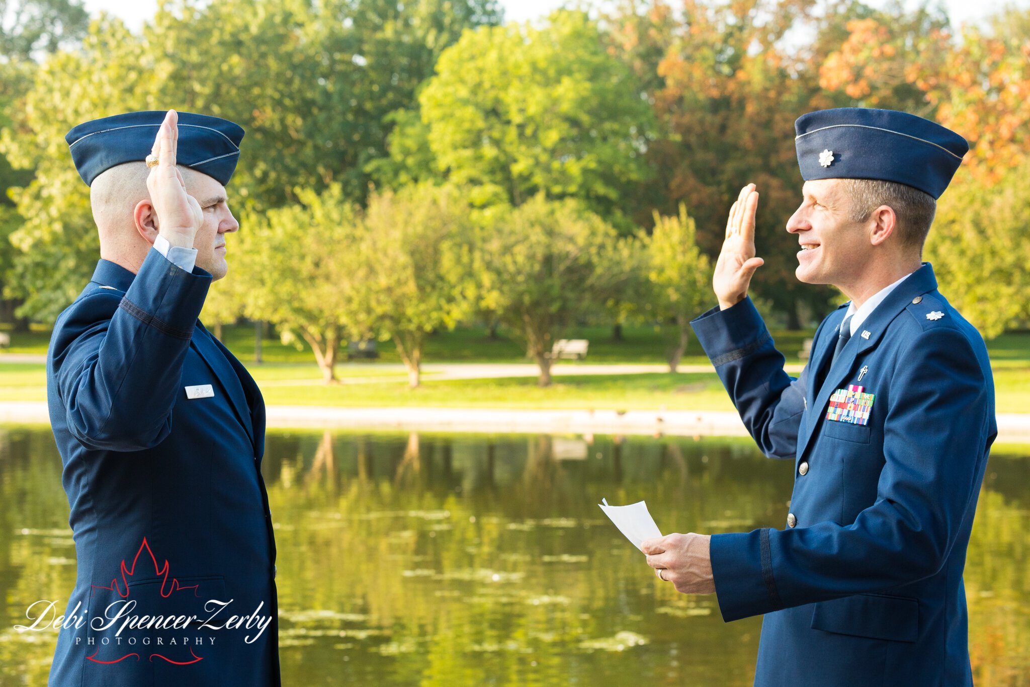 Two men in a park salute each other during a military ceremony photoshoot.