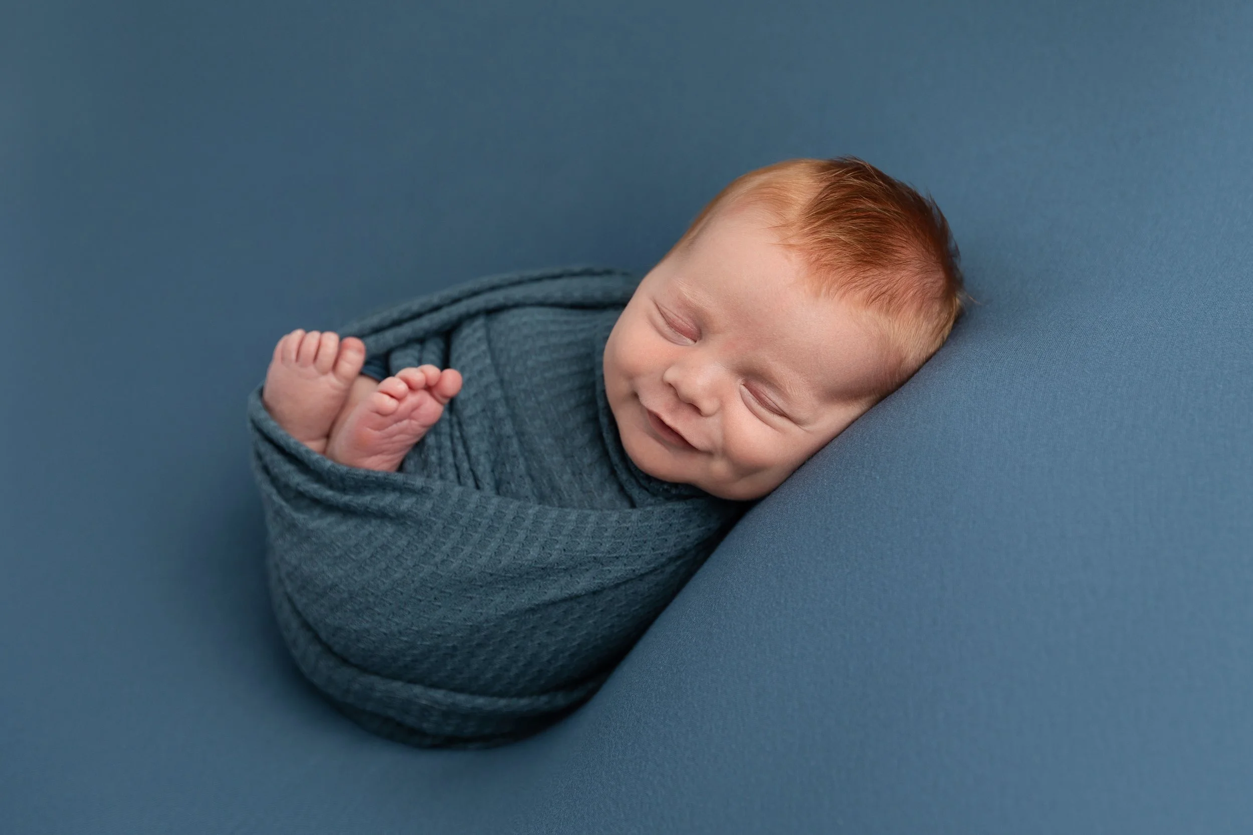 Smiling newborn baby boy in studio