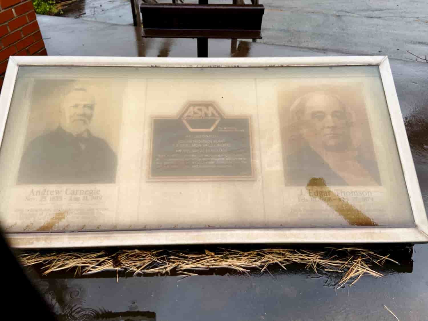  A plaque in front of the steel mill, dedicated to Andrew Carnegie and J. Edgar Thomson, is covered in soot. 