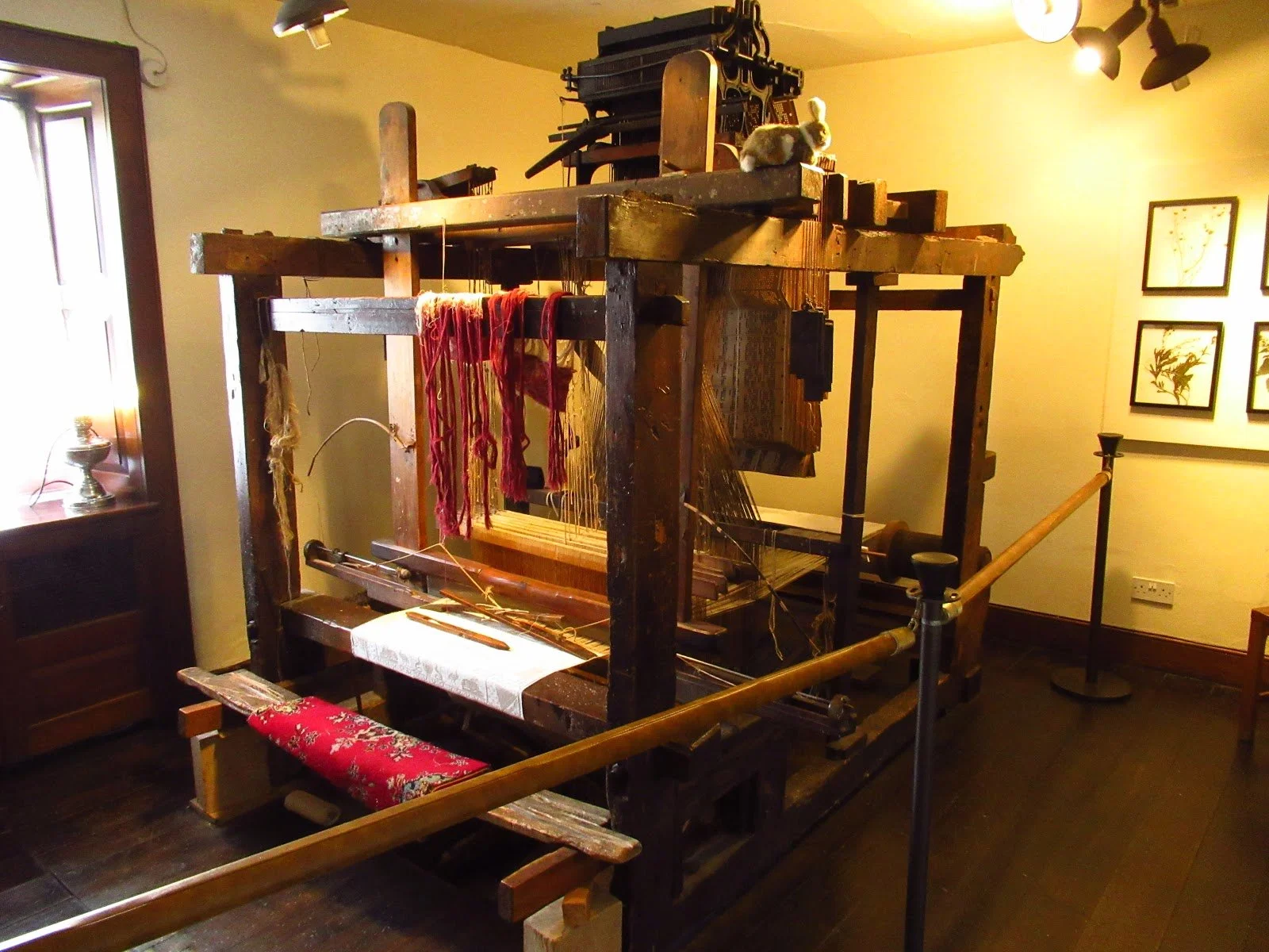 Wooden construction is a Jacquard loom which has a netal machine to read cards on the top.
