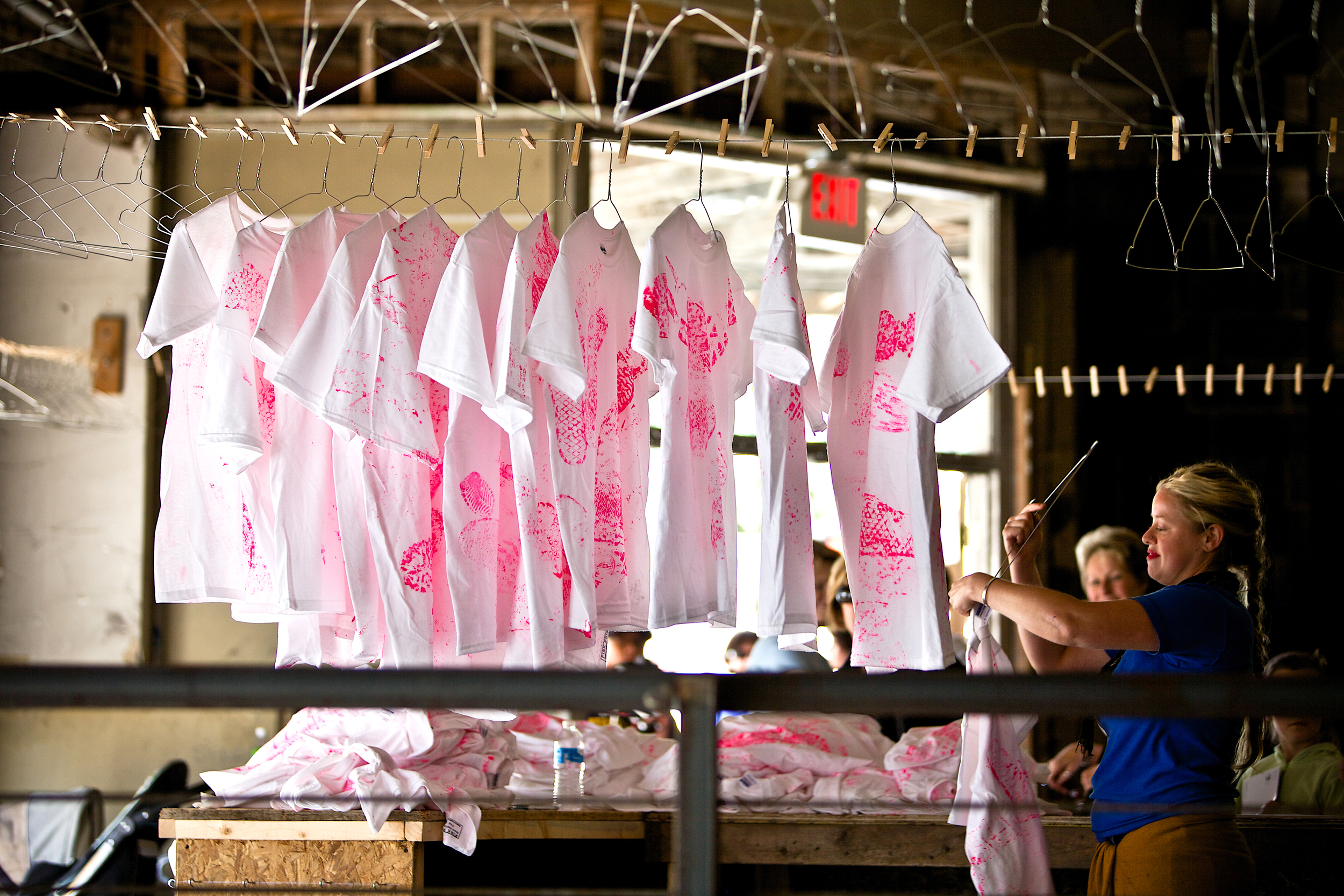 Pink Prints - Grand Rapids Streetwear Assocreation ASSOCREATION (founded in 1997) is an artist collective based in Vienna (Austria) and Ann Arbor, Michigan. The group considers itself an individual. Its agents work anonymously. ASSOCREATION involves the public in an open play, while exploring the way human beings relate to both the space around them and the ground beneath their feet. ASSOCREATION has presented among others at Jack the Pelican Gallery in Brooklyn (NY), Fabrica Gallery Brighton (UK), the Bienal de Valencia (Spain), the Ars Electronica Festival in Linz (Austria), as well as in the streets of New York, Warsaw, Zurich, Copenhagen and Paris. Hundreds of white t-shirts are on the street in Downtown Grand Rapids. People are invited to slip into shoes that are provided, step into pink paint and walk all over the clothing. They leave their traces on the shirts, which are displayed afterward in the former Junior Achievement Building at the corner of Division and Fulton in Downtown Grand Rapids. Once dry, the shirts are sold and worn as clothing. Yesterday’s steps are dispersed on apparel fabric in all directions. Happening and dispersal are a scatter diagram imaging Grand Rapids. The former Junior Achievement building, as a short-term cluster in this diagram, turns into an urban outlet that sells Grand Rapids Streetwear – the materialization of the sole’s eeting contact with the ground – the concurrence of street, steps, clothing, dirt and paint.