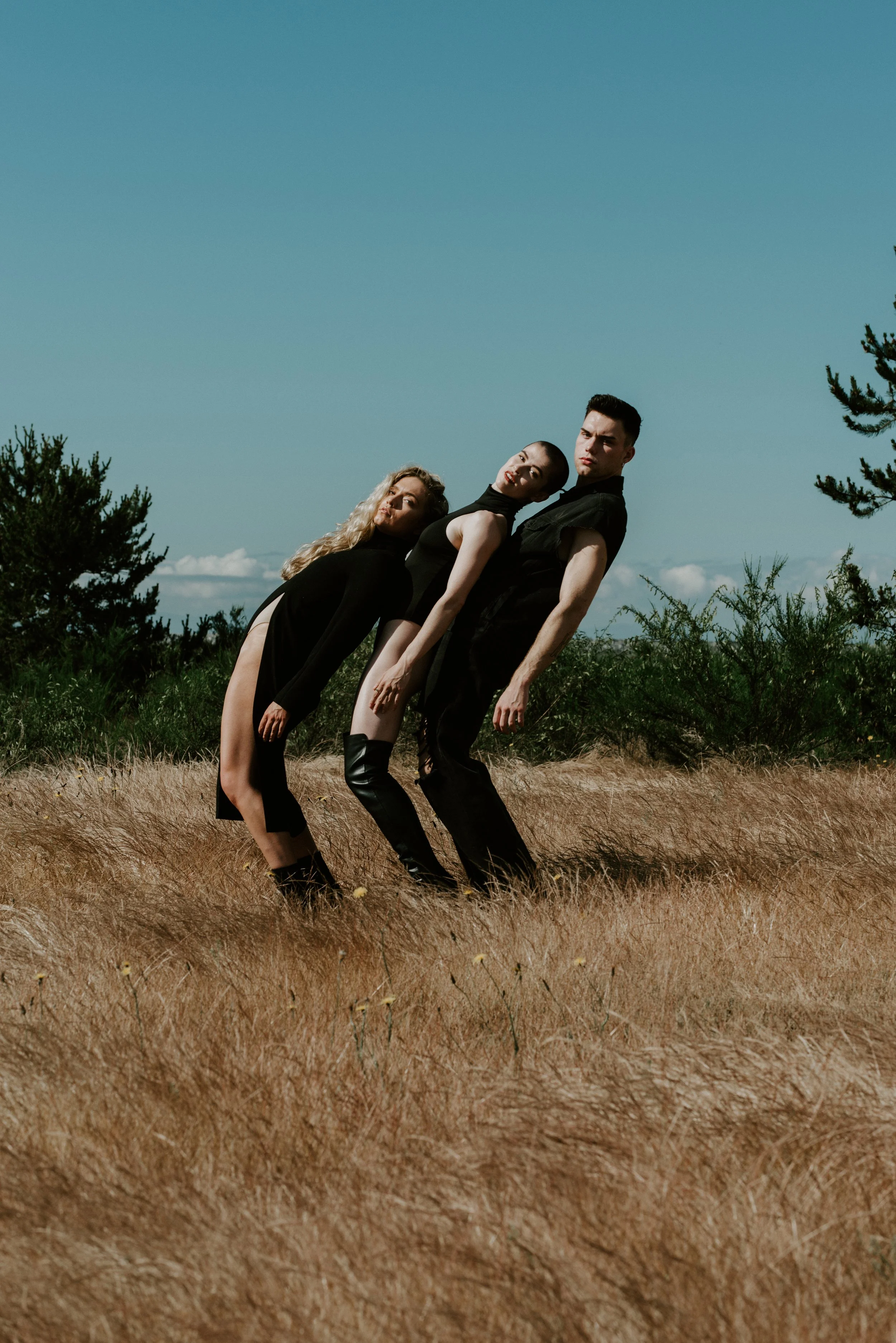 three-dancers-leaning-blue-sky-field.jpg