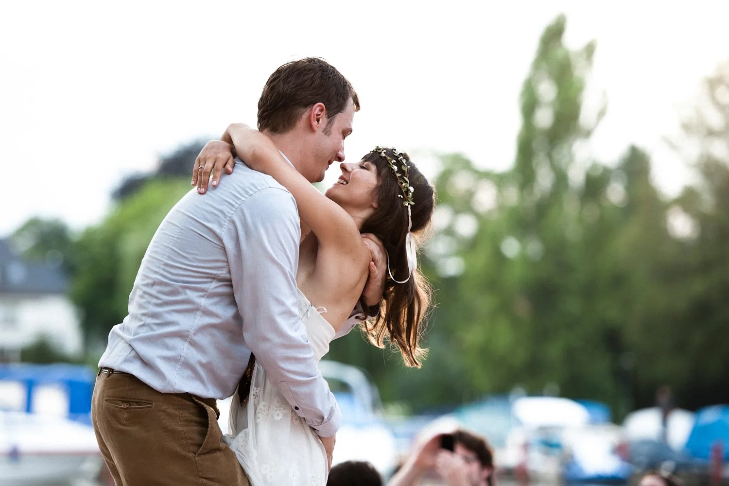 Bride and groom laughing and dancing together outdoors.