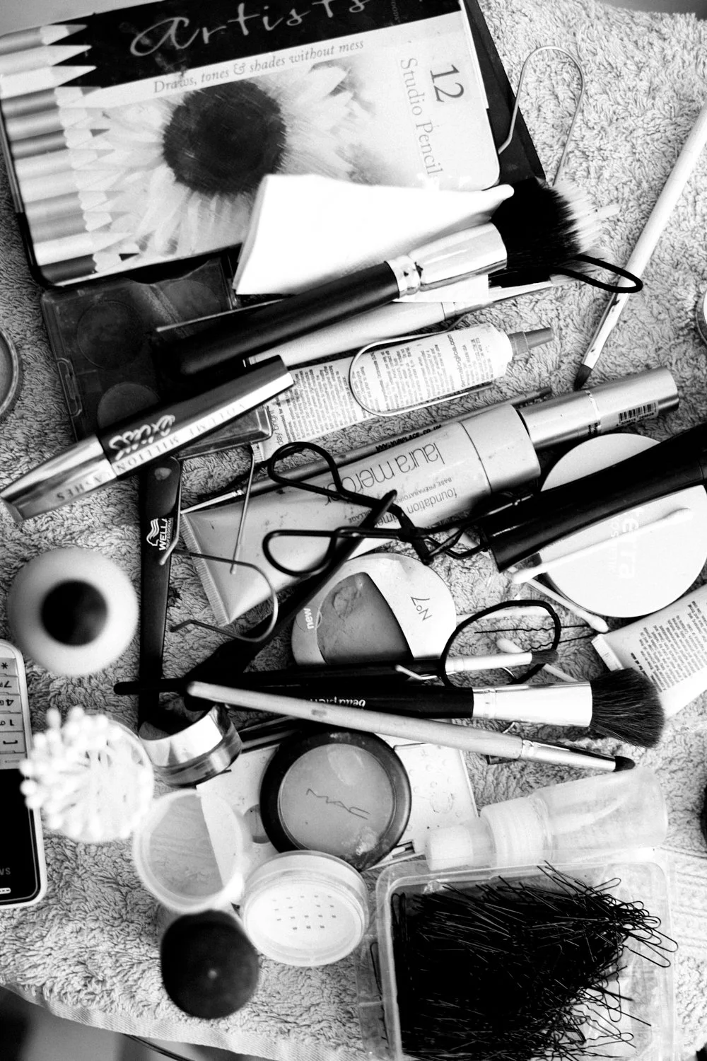 Various make-up utensils and cosmetics on a towel.