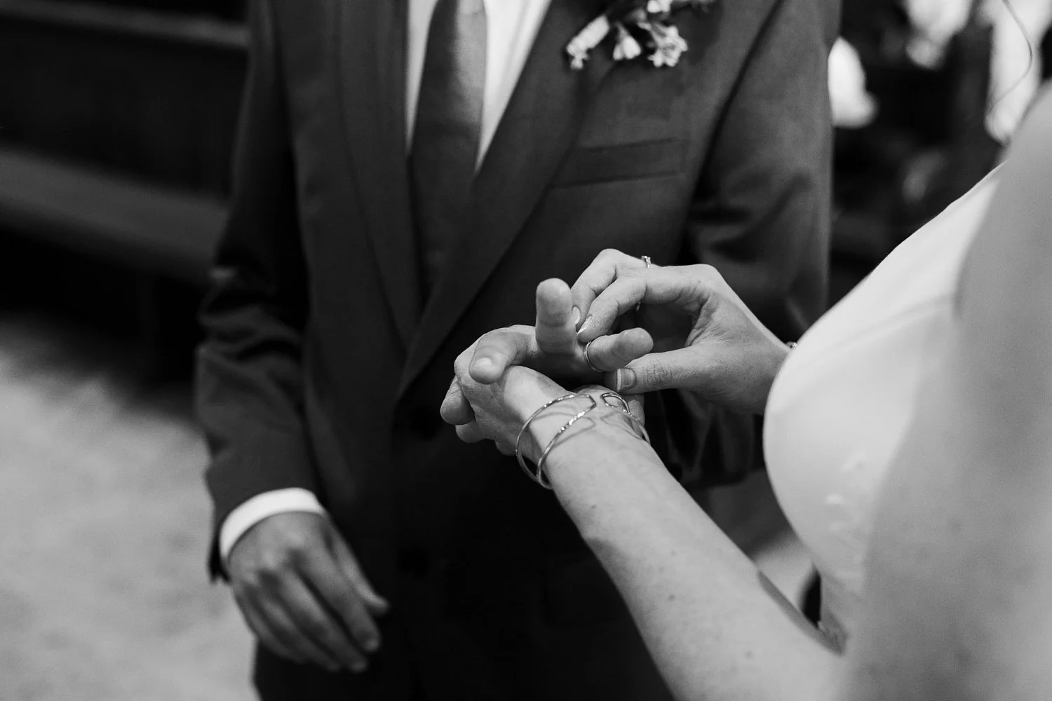 Die Braut steckt den Ehering an den Finger des Bräutigams.