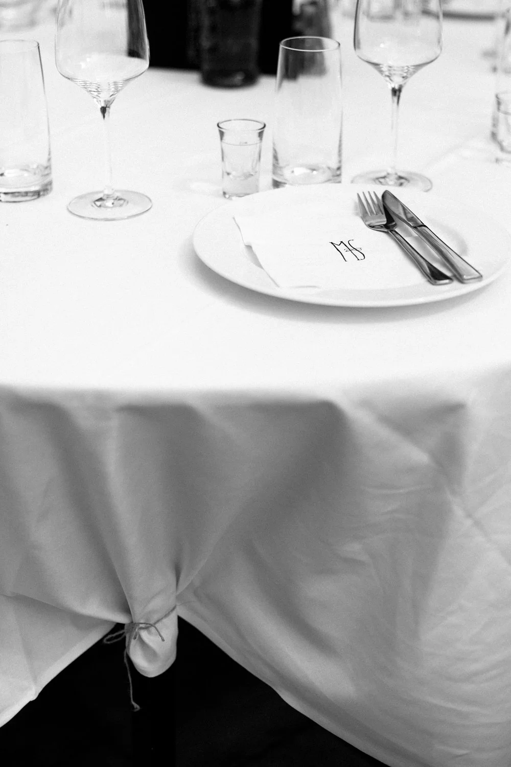 Table with a white table cloth, glasses, a plate and cutlery.
