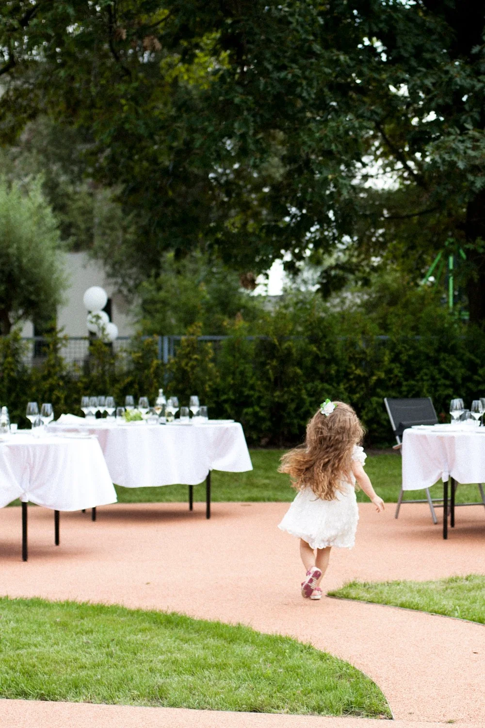 A girl with long hair running between tables set for a wedding reception.