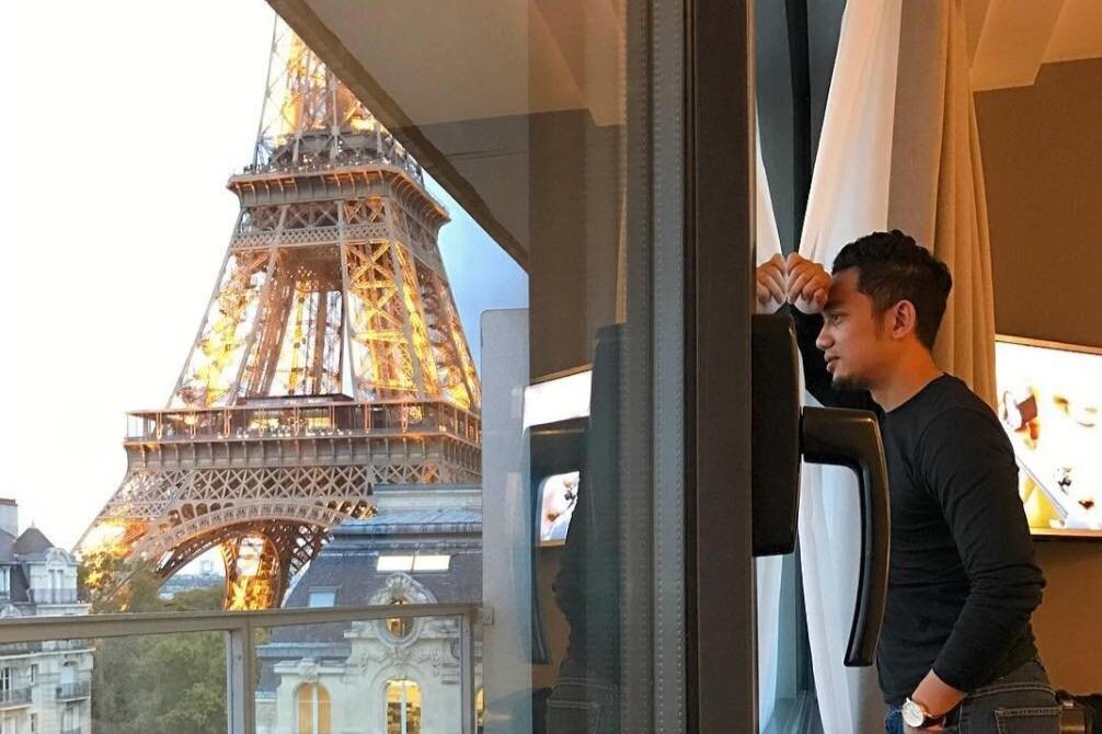 Man overlooks the Eiffel Tower from his room window