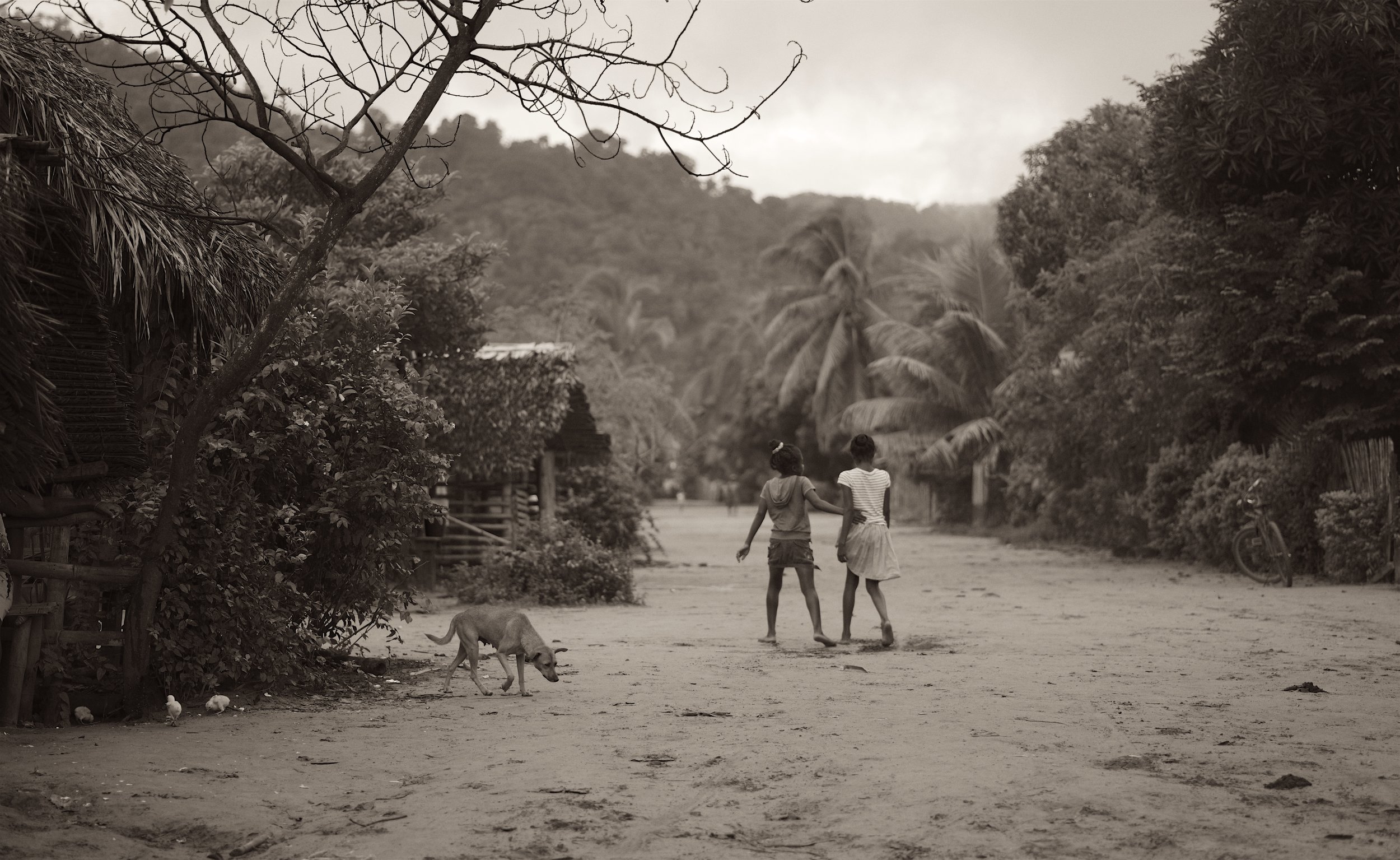 Village Tracks Two sisters walk arm in arm down one of Mangabe’s dusty roads.