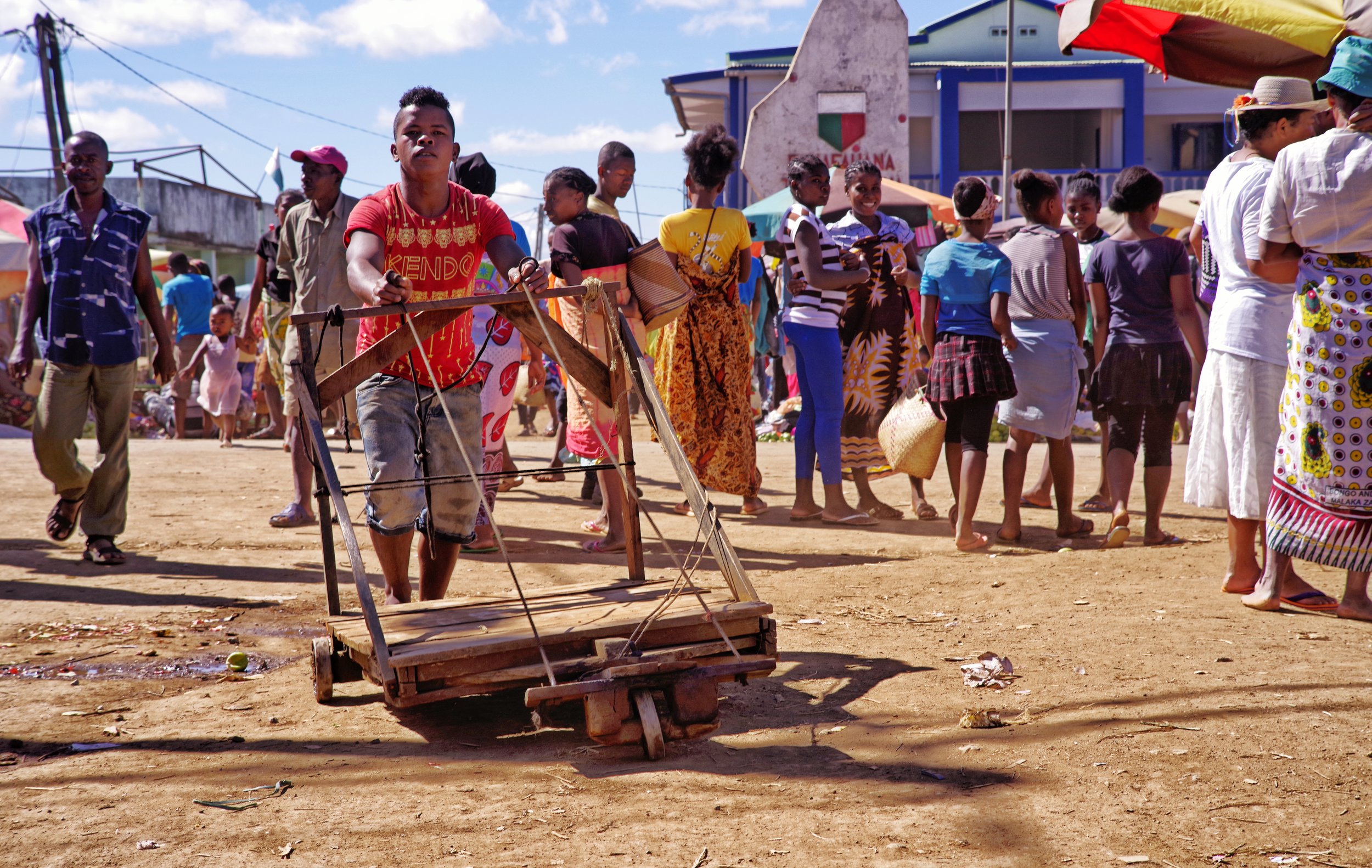 Unidentified Rolling Object A boy wheels some contraption along the sandy floor of a Malagasy village. Sunday mornings often offer up the best market pieces.