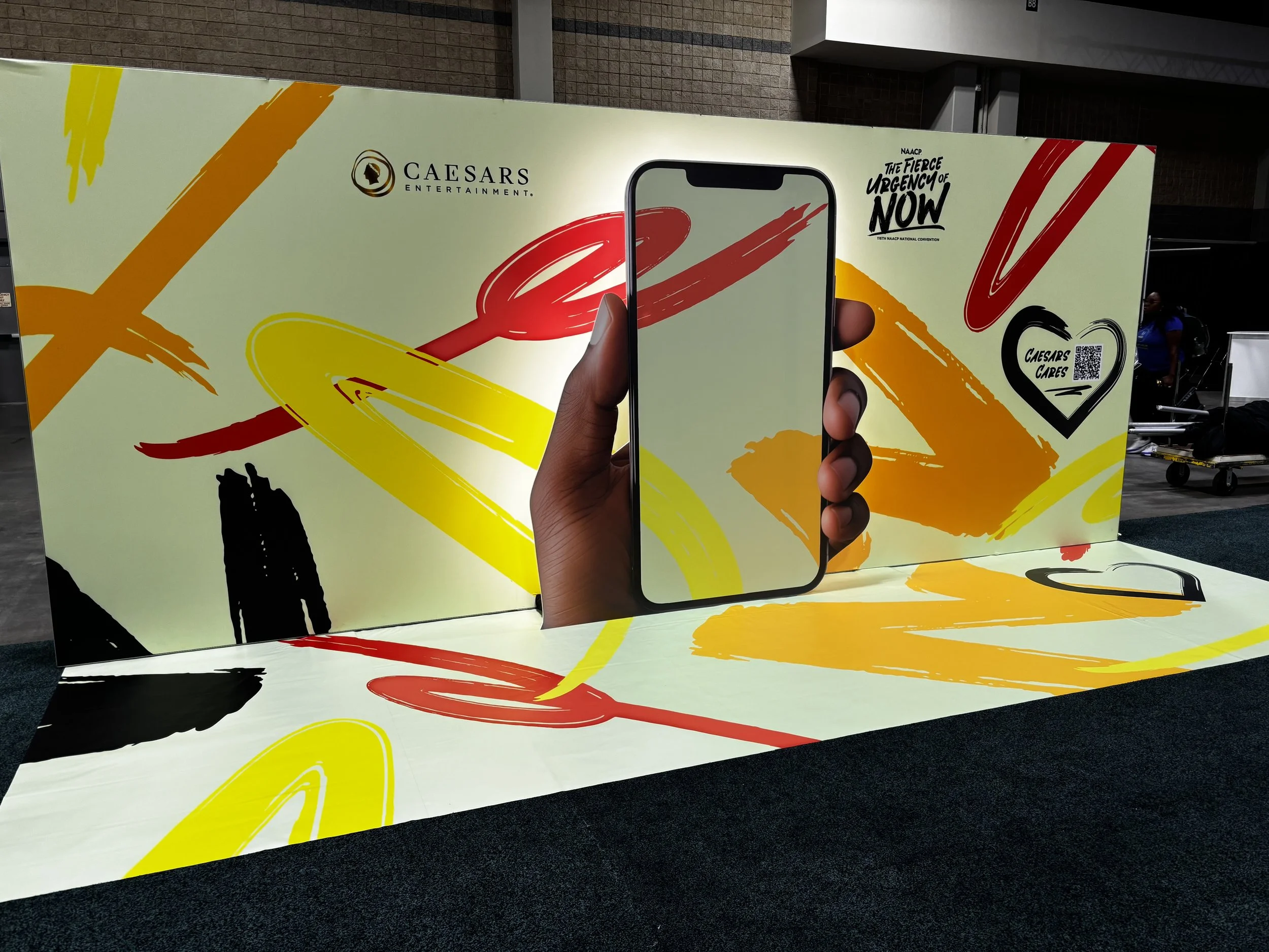 To encourage engagement and shareable moments, a large-scale photo installation featured a 3D hand holding a cell phone in front of a vibrant, event-branded backdrop. Designed to mirror the energy and creativity of the convention, this playful setup