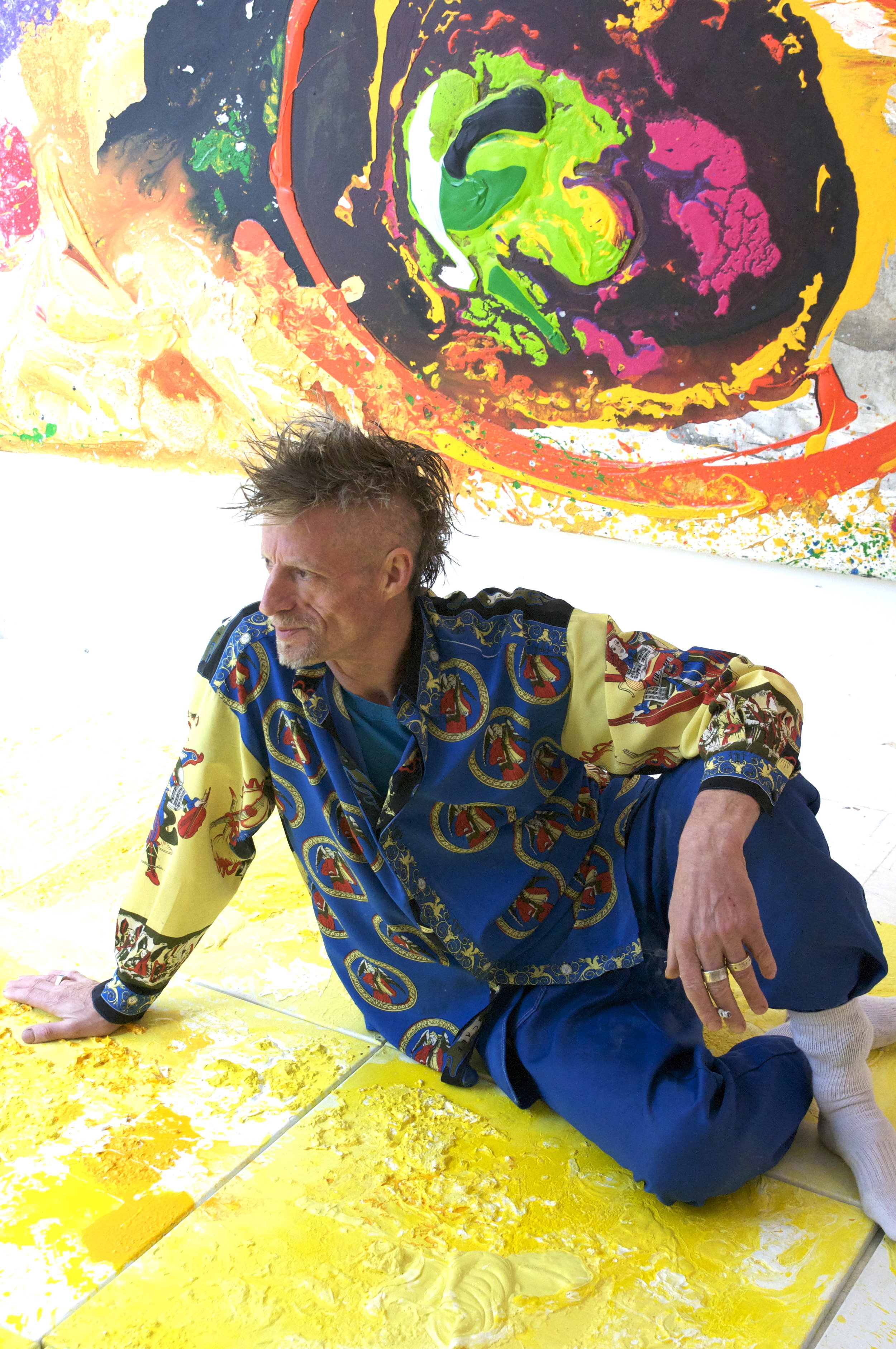 Harry sitting with his colorful abstract paintings
