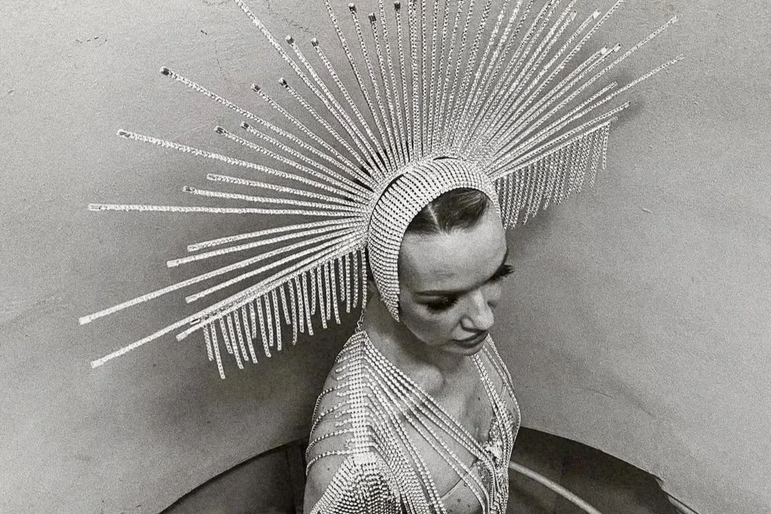 Donna elegante con copricapo di diamanti che esegue un trucco di magia durante un matrimonio, creando un’atmosfera incantata e sofisticata.