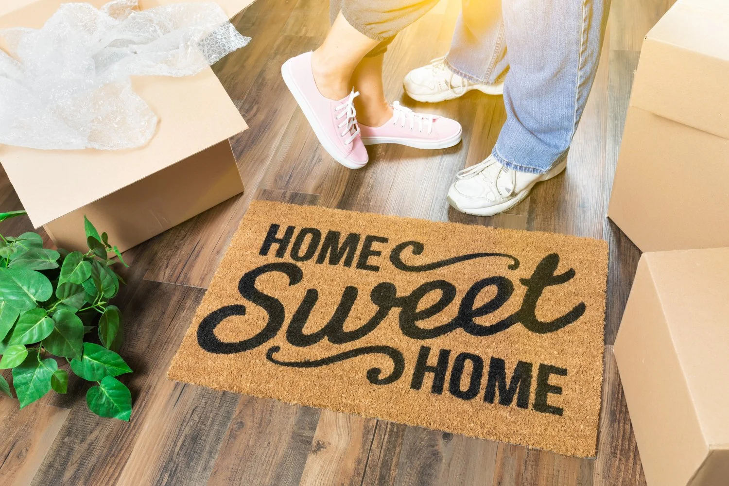 Home Sweet Home welcome mat and moving boxes representing new homeownership.