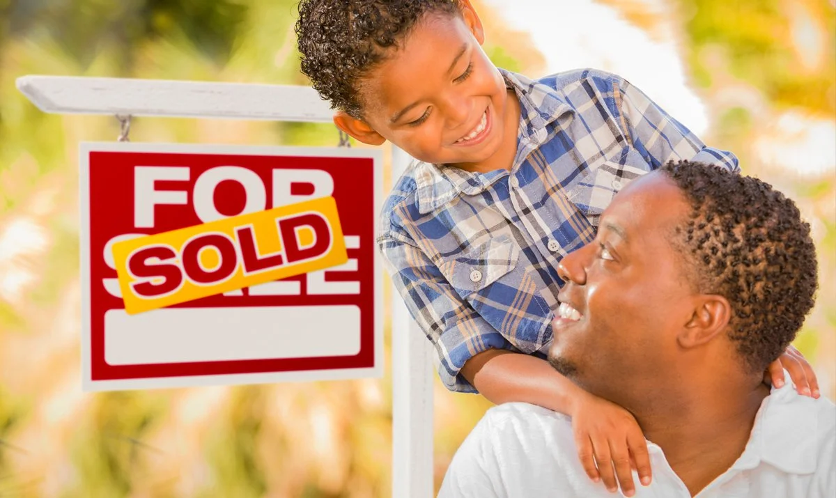 Family celebrating homeownership in front of a home with a sold sign.