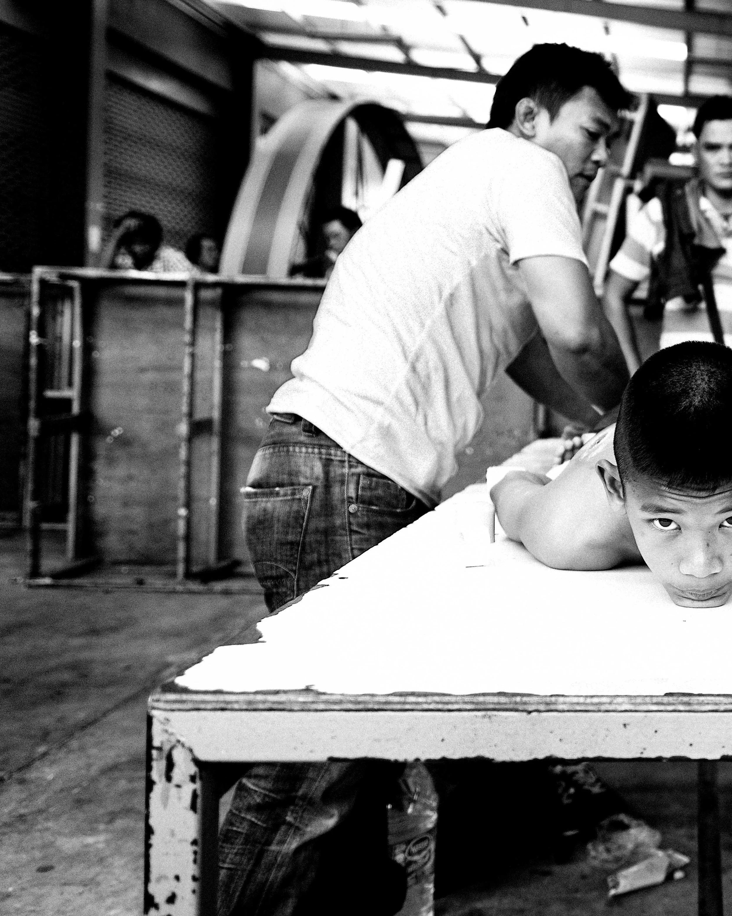 A fighter notices my camera while being massaged in the dressing area of Channel 7 Stadium. #muaythai