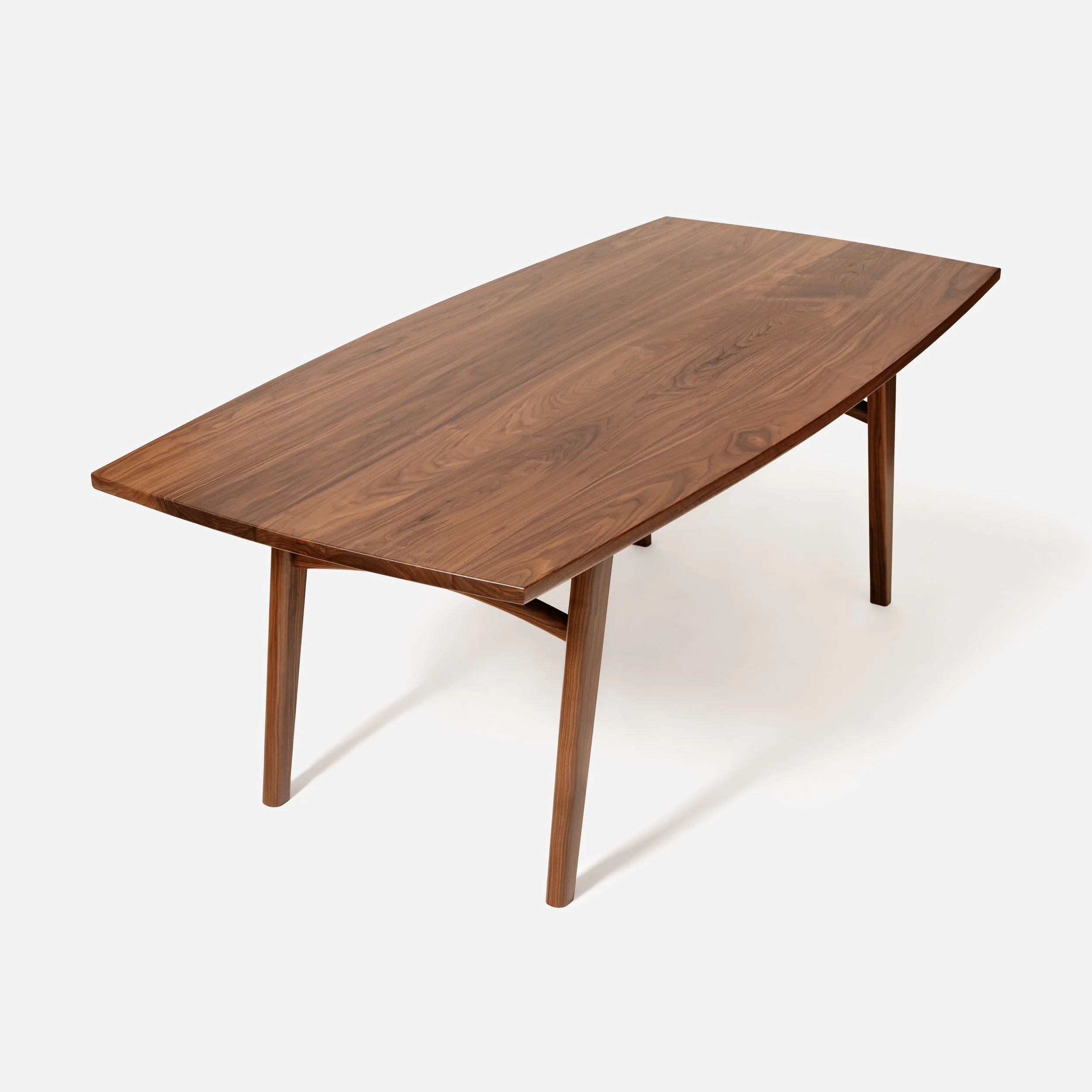 Profile view of a modern walnut table with an arched apron, splayed legs, and a sculpted undercarriage by Sustar Woodworks.